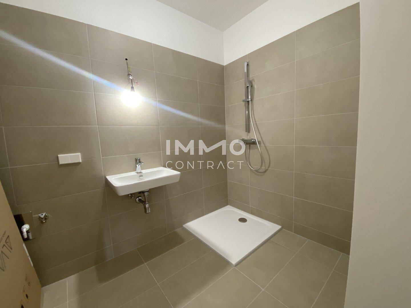 Modernes Badezimmer mit beigefarbenen Fliesen, Dusche und Einzelwaschbecken.