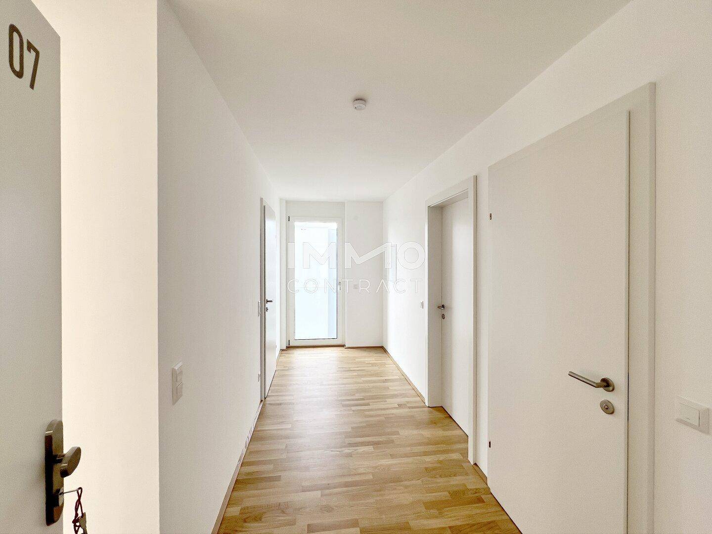 Langer, heller Flur mit Holzboden und mehreren Türen zu den angrenzenden Zimmern.