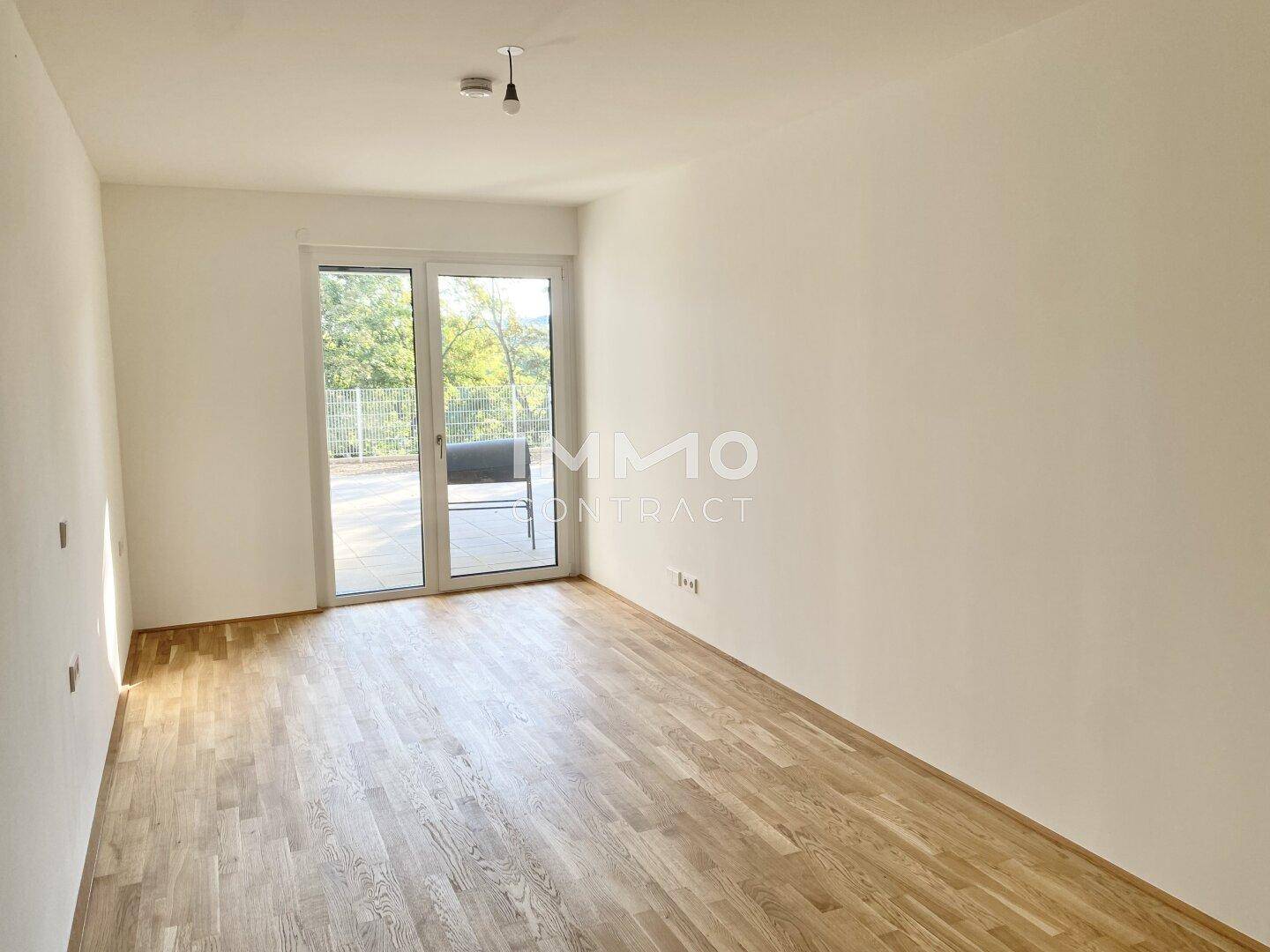 Geräumiges Zimmer mit Holzboden und direktem Zugang zu einer Terrasse.