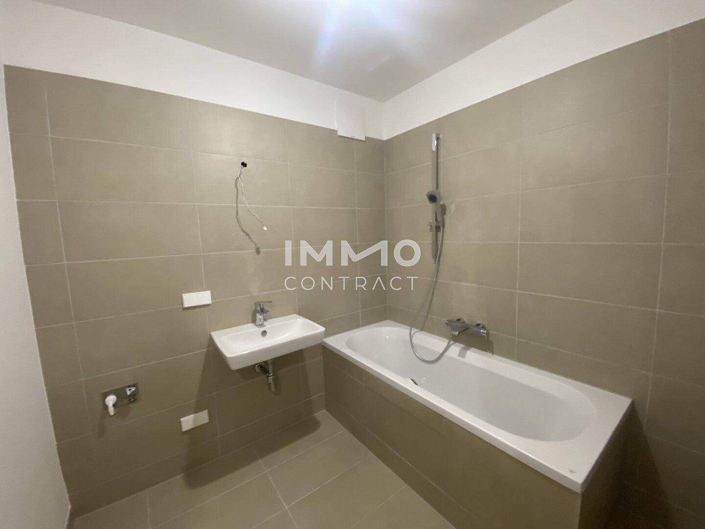 Badezimmer mit beigefarbenen Fliesen, Badewanne und Einzelwaschbecken.