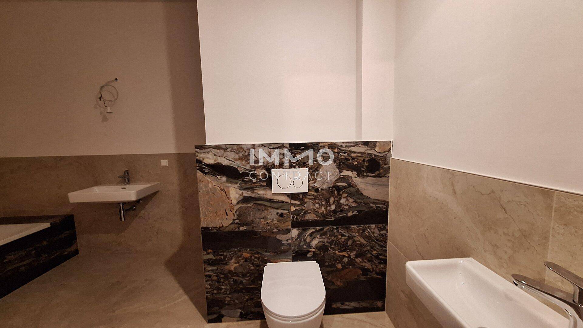 Modernes WC mit Wand-WC und stilvollen Fliesen, ergänzt durch ein Waschbecken.