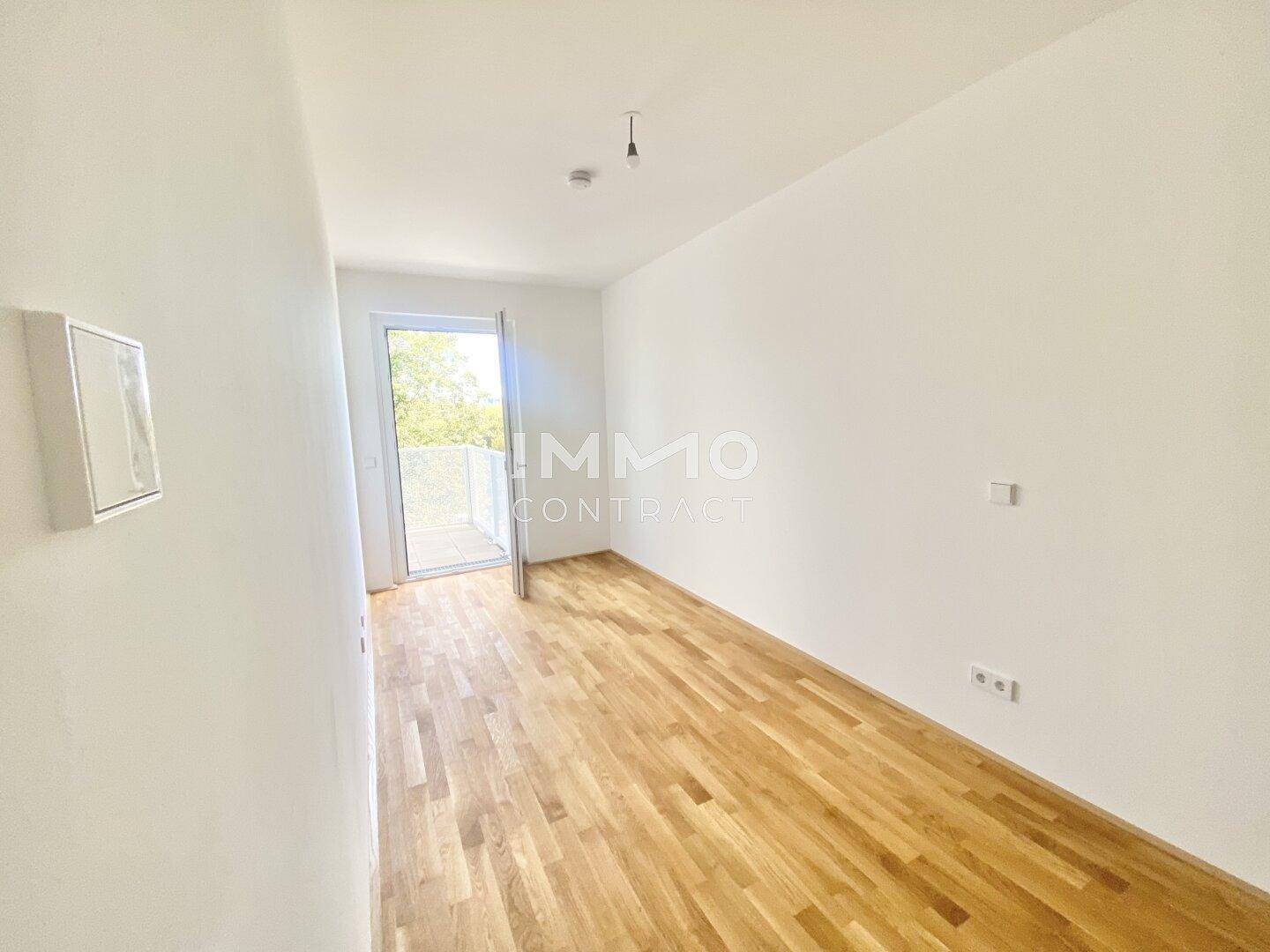 Heller Raum mit Holzboden und Zugang zu einem Außenbereich, vielseitig nutzbar.
