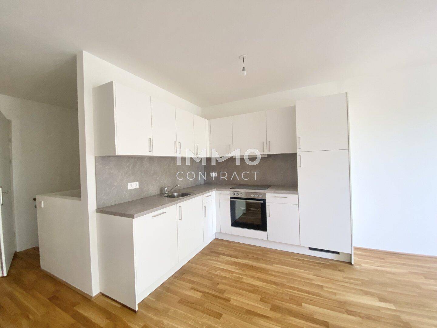 Moderne Einbauküche in Weiß mit integrierten Geräten und Holzboden.