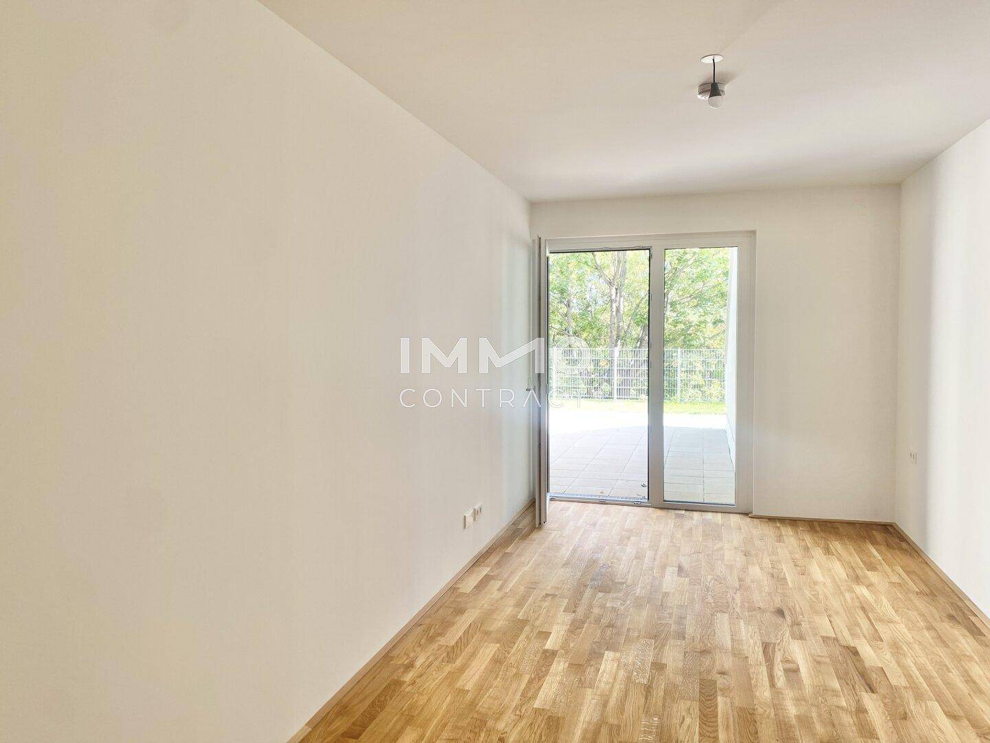 Lichtdurchfluteter Raum mit Holzboden und direktem Zugang zu einem Außenbereich.