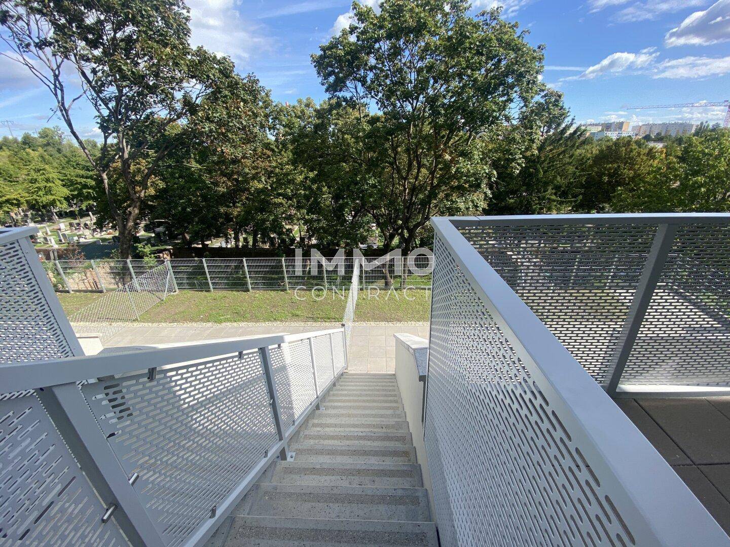 Moderne Außentreppe mit Lochblechgeländer, führt zu den oberen Wohneinheiten.