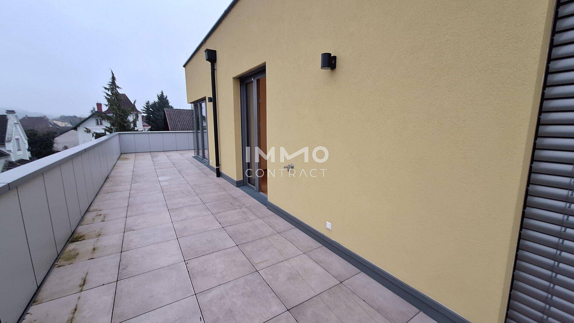 Weitläufige Dachterrasse mit Fliesenboden und Blick auf die umliegende Bebauung.