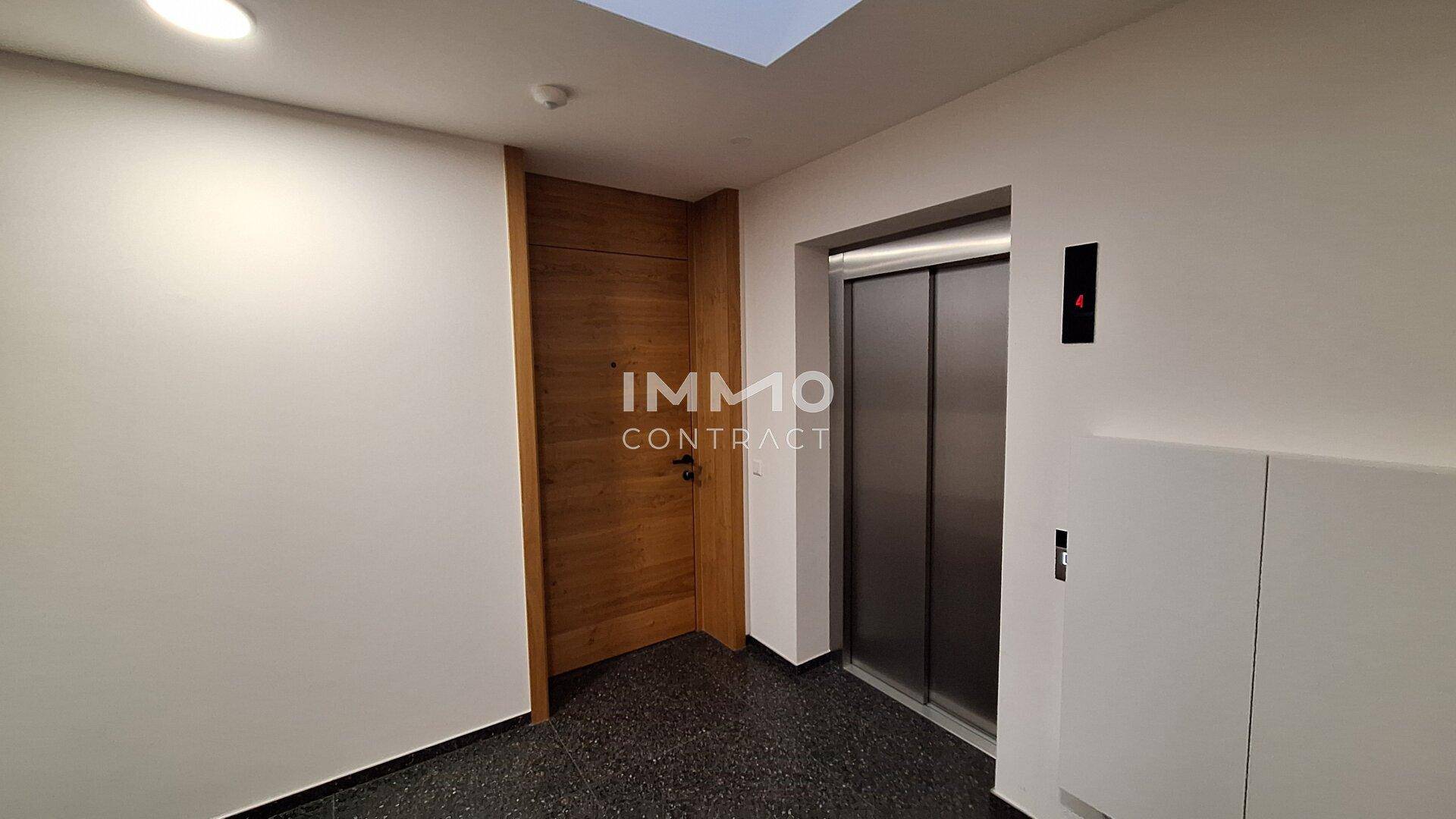 Moderner Eingangsbereich mit Aufzug und Holzdetails, der zu den Wohneinheiten führt.