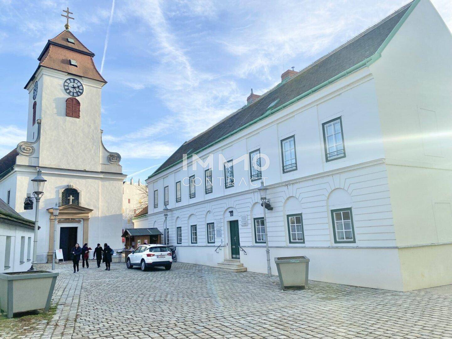 Historische Kirche und ein großes weißes Gebäude an einem sonnigen Tag.