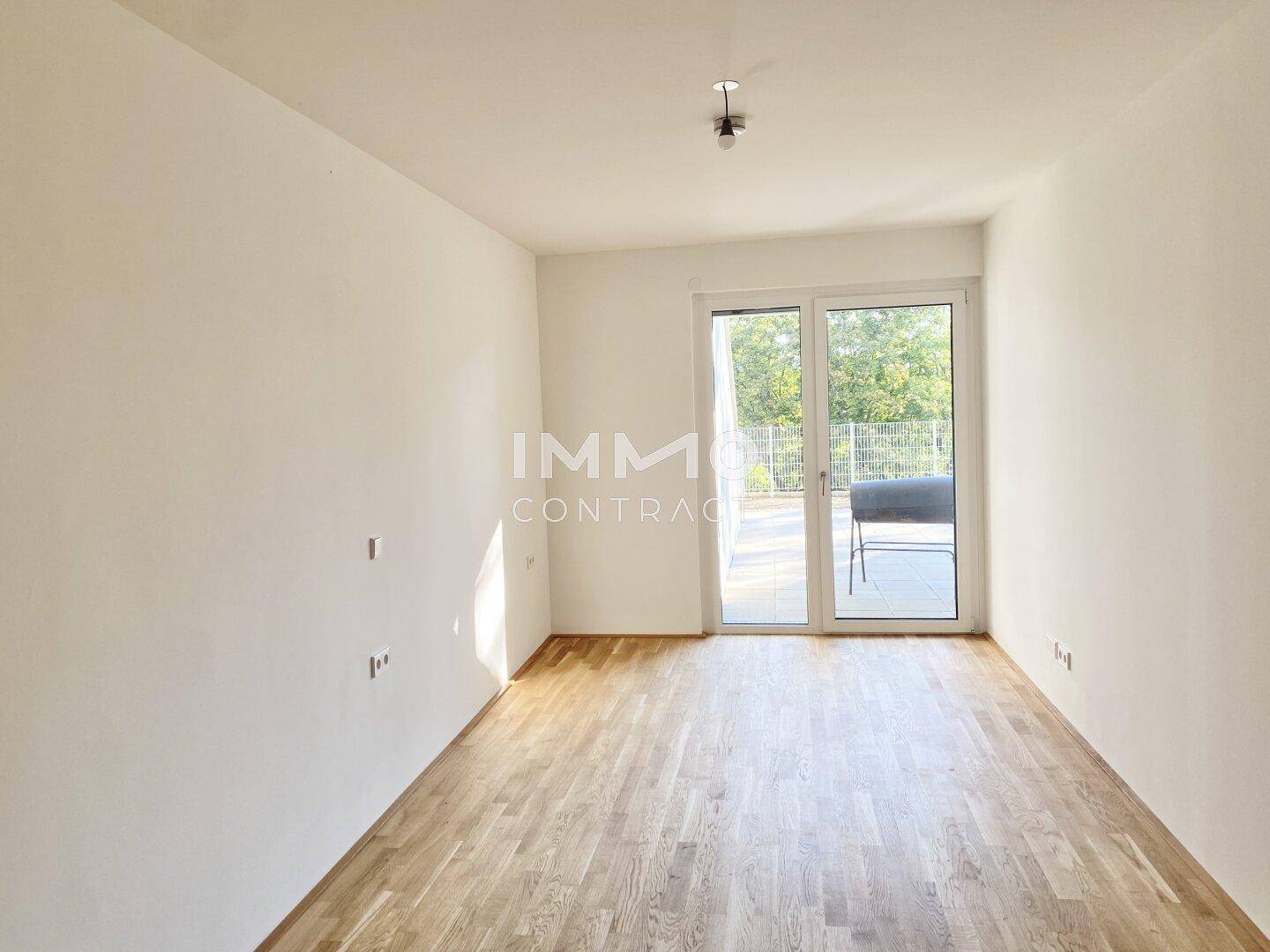 Geräumiger, leerer Raum mit Holzboden und Zugang zu einem Außenbereich.