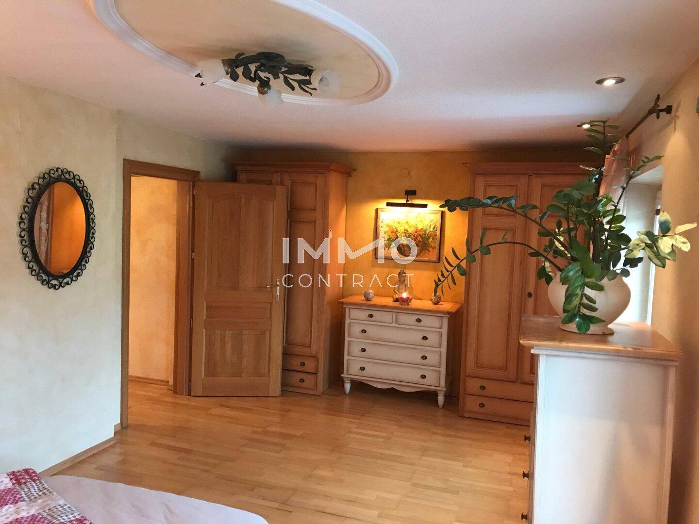Geräumiges Schlafzimmer mit Holzmöbeln, Parkettboden und dekorativer Deckengestaltung.