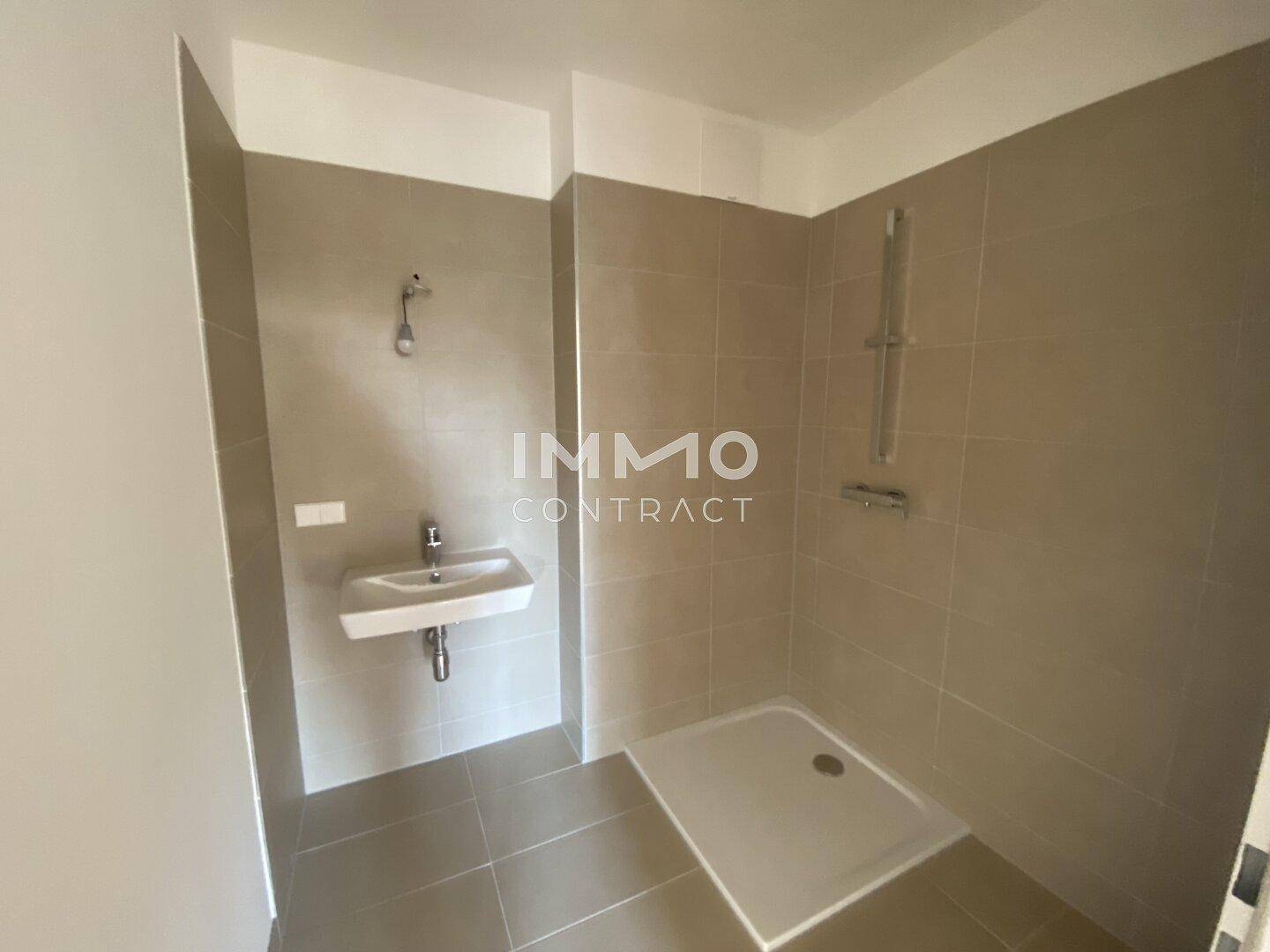 Modernes Badezimmer mit ebenerdiger Dusche, Waschbecken und grauen Fliesen.