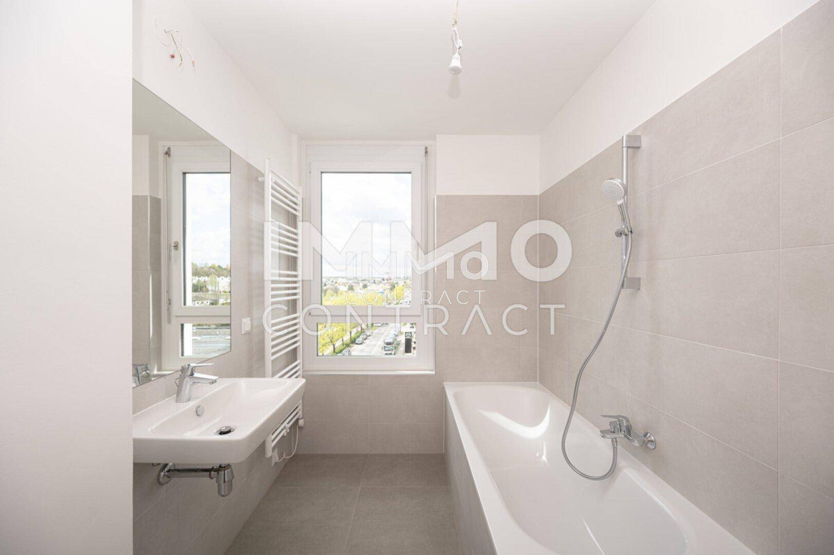 Modernes Badezimmer mit Badewanne, Waschbecken, beheiztem Handtuchhalter und Fenster.