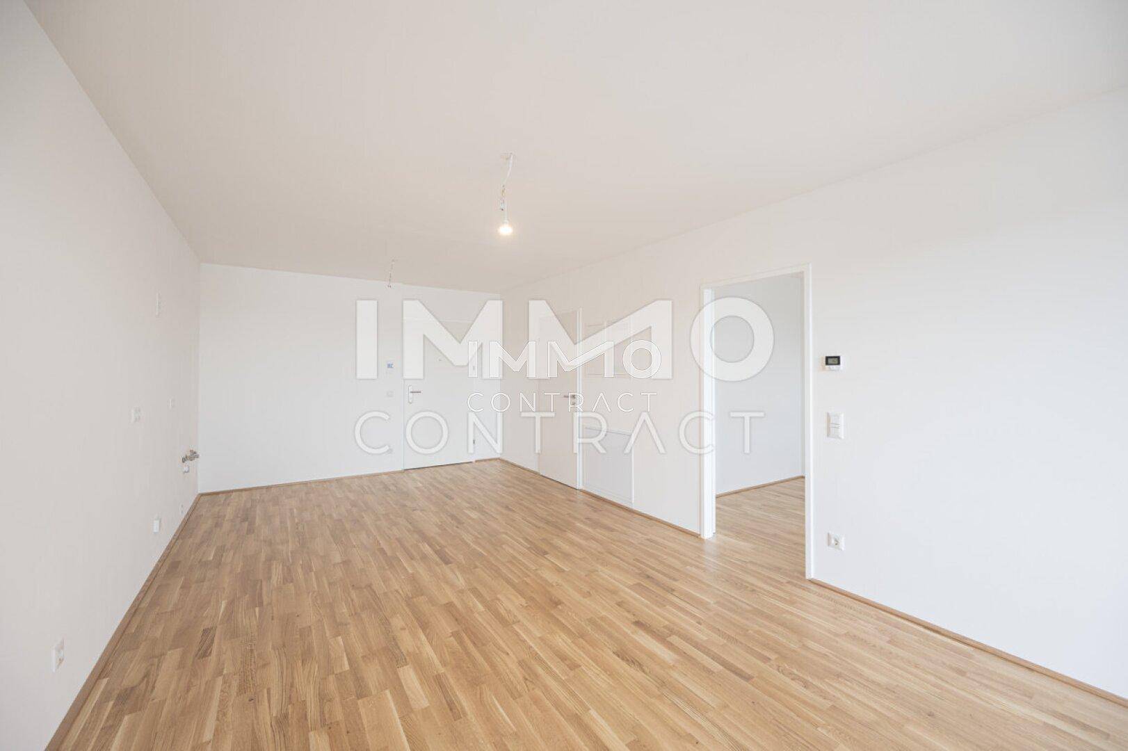 Geräumiges, leeres Zimmer mit hellem Parkettboden und weißen Wänden, bereit zum Einzug.