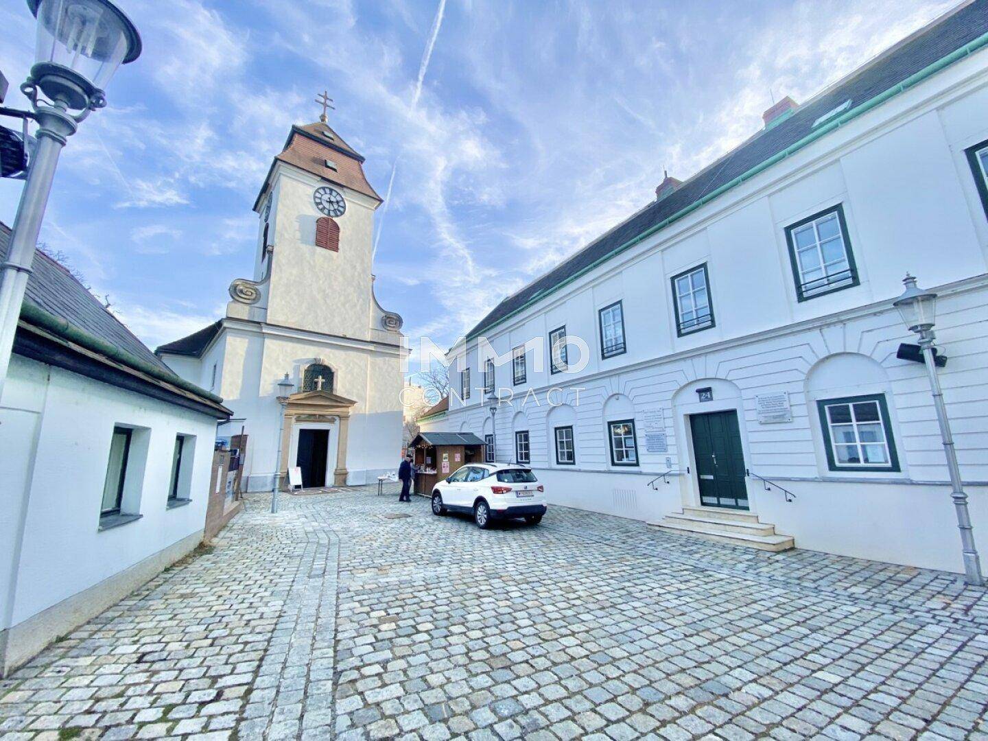 Malerische Gasse mit Kopfsteinpflaster, historischer Kirche und einem weißen Gebäude.