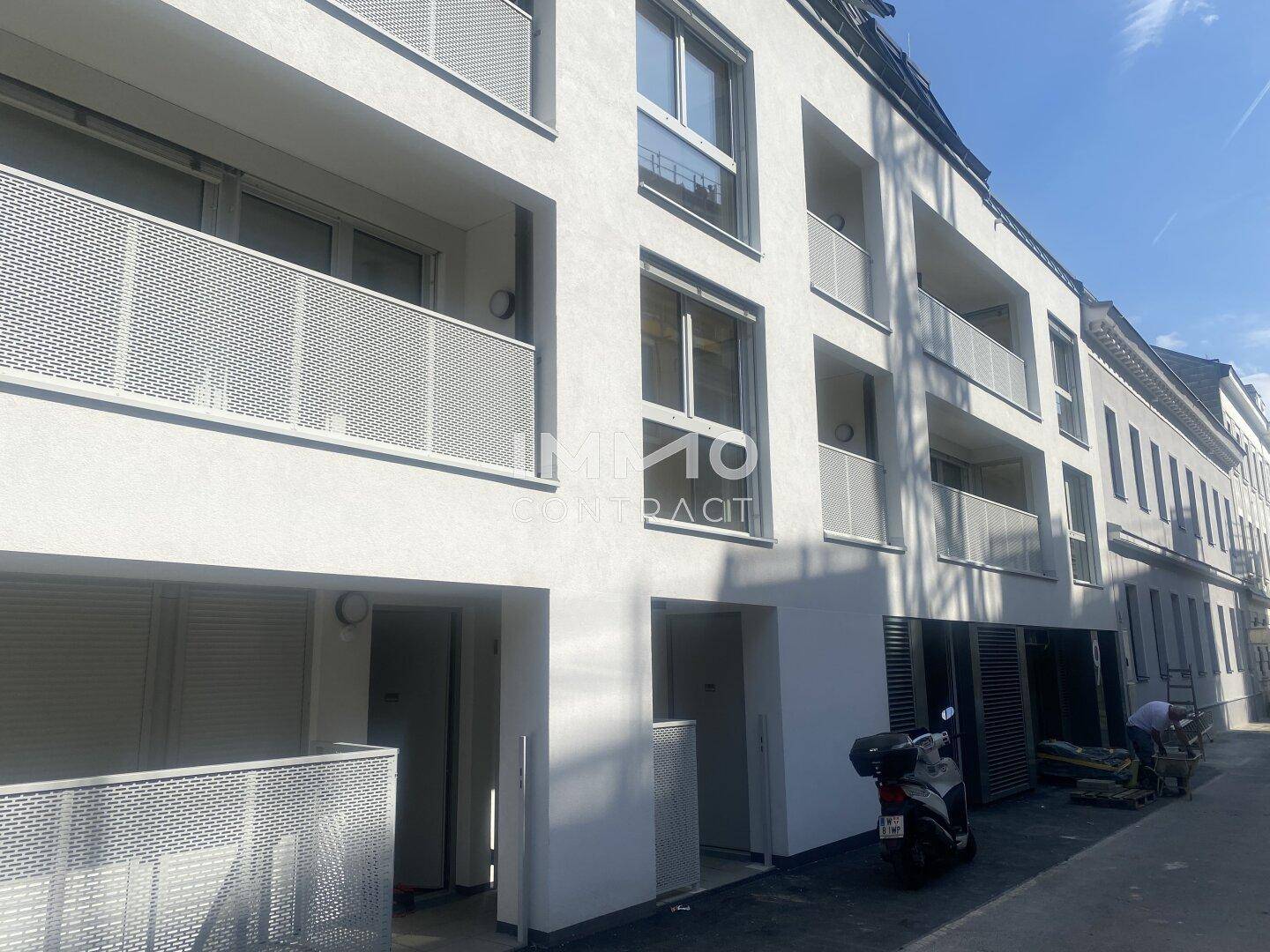 Moderne Wohngebäude-Fassade mit Balkonen und großen Fenstern in städtischer Umgebung.