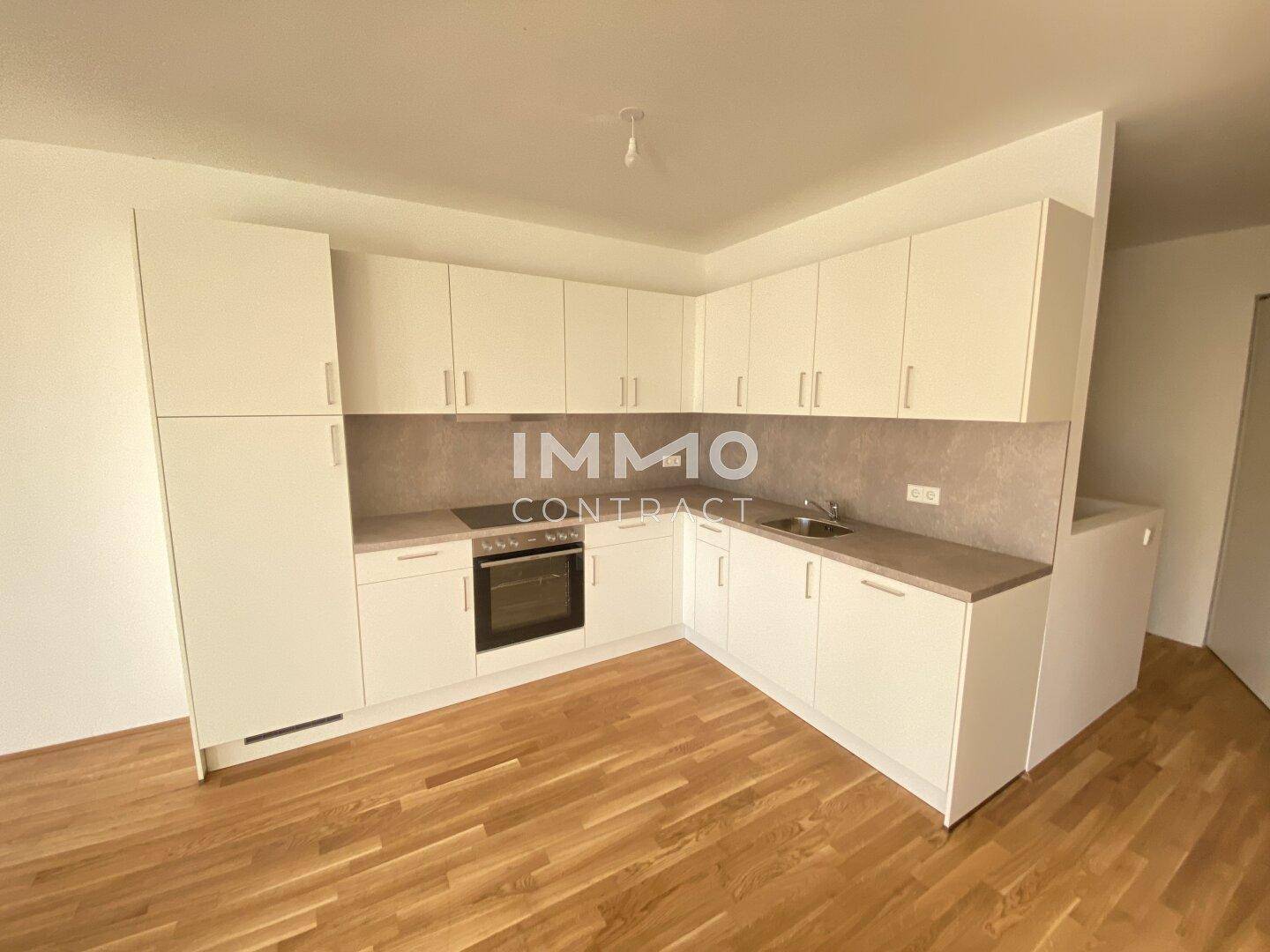 Moderne Einbauküche in Weiß mit integrierten Geräten und hellem Holzboden.