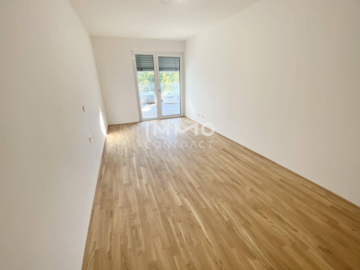 Heller, unmöblierter Raum mit Holzboden und Zugang zu einem Balkon, ideal als Schlafzimmer.