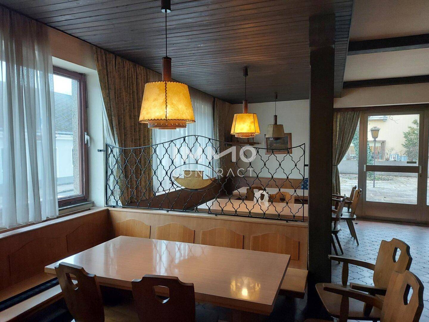 Essbereich mit Holztischen, Bänken und dekorativen Lampen.