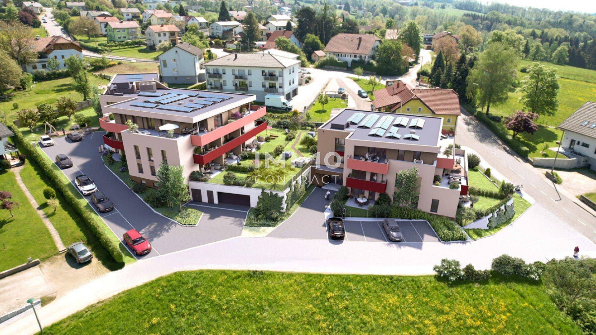 Weitläufige Luftaufnahme einer modernen Wohnanlage mit mehreren Gebäuden und viel Grün in ländlicher Umgebung.