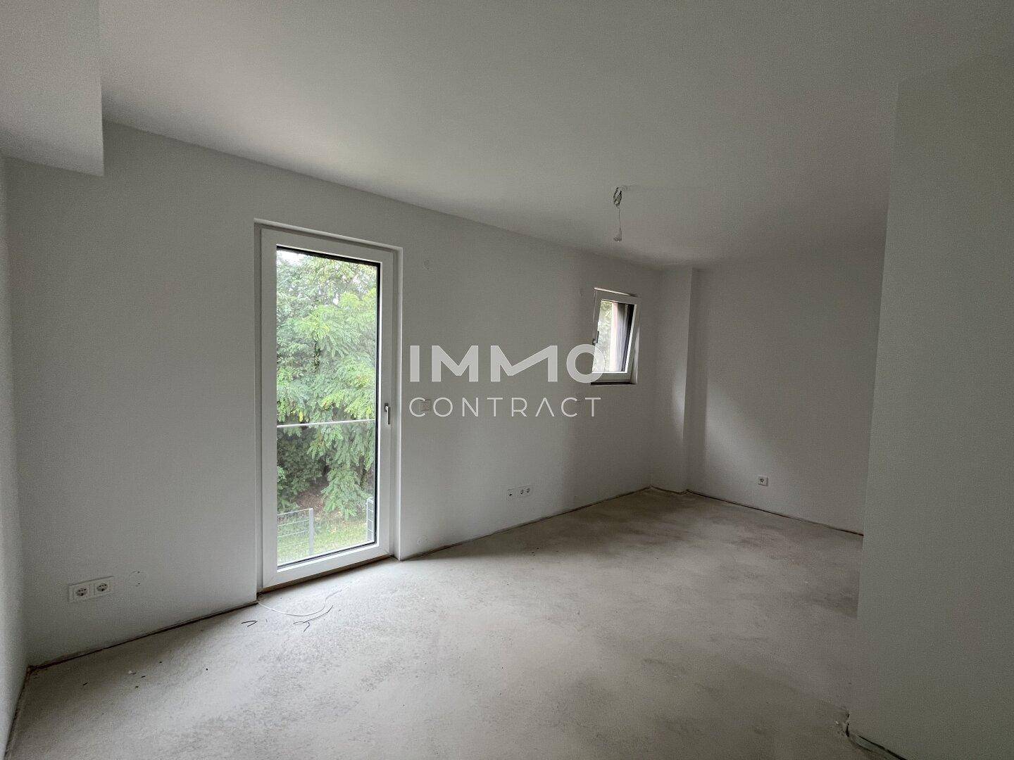 Unfertiges Zimmer mit Zugang zum Außenbereich und Blick ins Grüne.