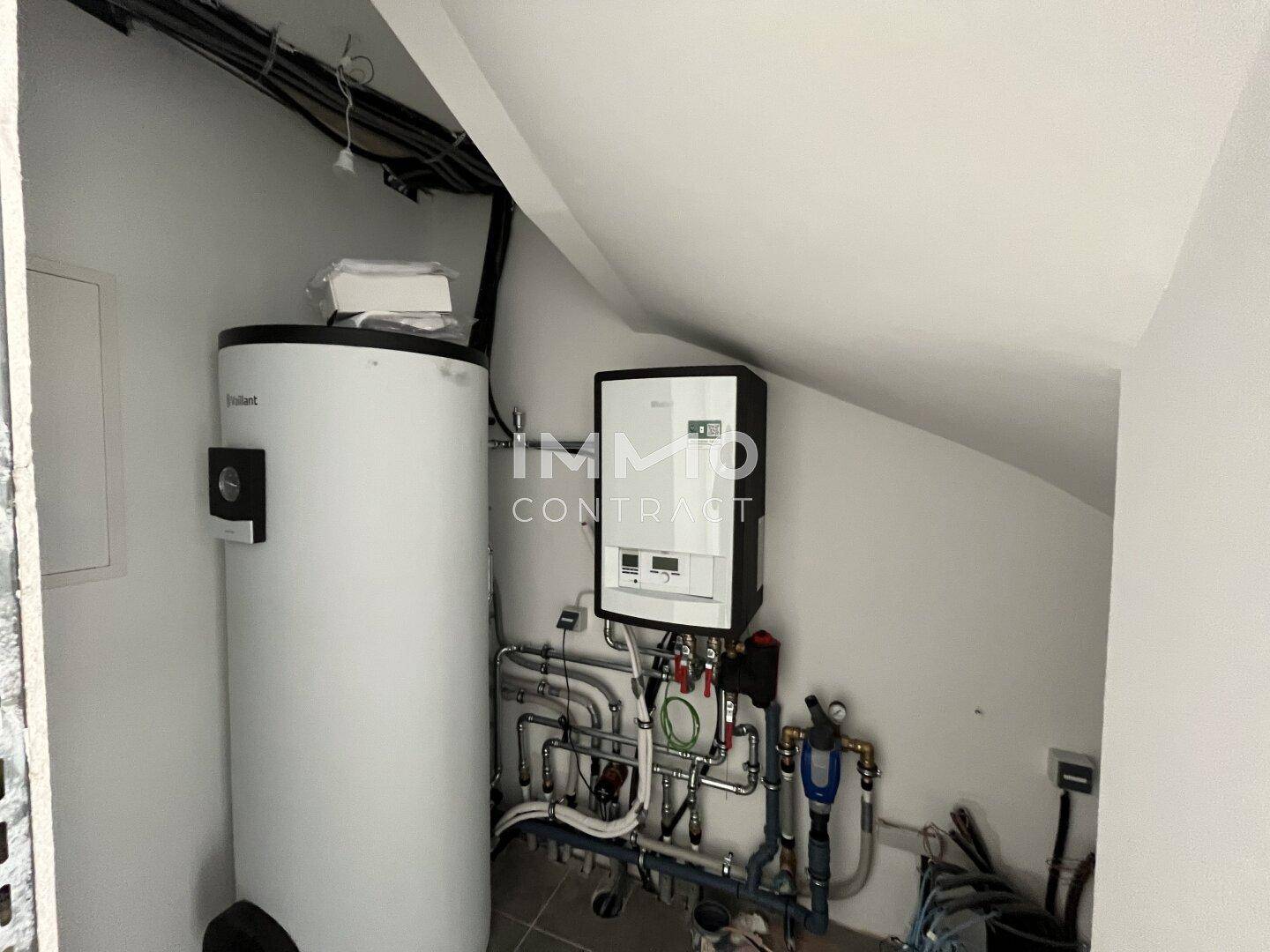 Technikraum mit Warmwasserspeicher und Heizungsanlage in einem Neubau.