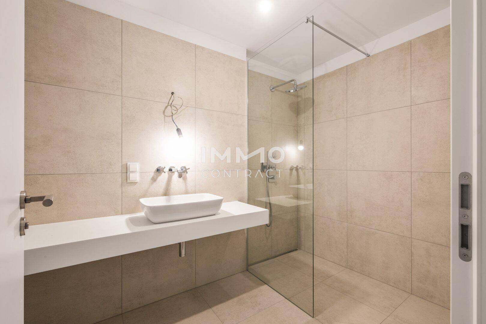 Modernes Badezimmer mit beigefarbenen Fliesen, ebenerdiger Dusche und Einzelwaschbecken.