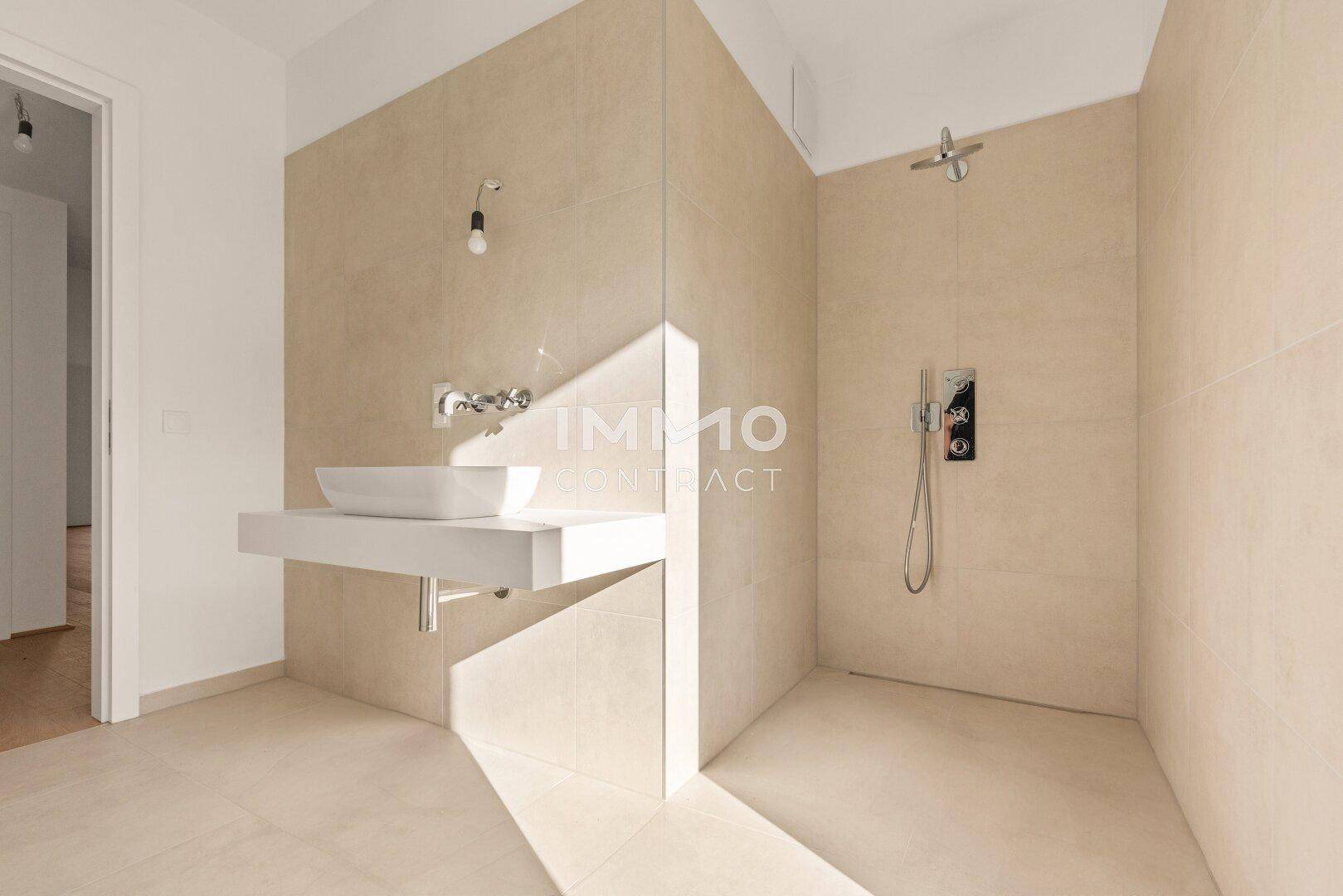 Elegantes Badezimmer mit beigefarbenen Fliesen, modernem Waschbecken und ebenerdiger Dusche.