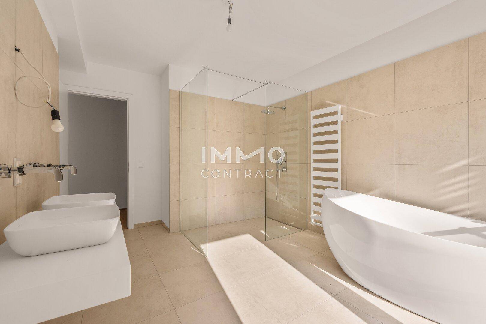 Großes, modernes Badezimmer mit freistehender Badewanne, Glasdusche und Doppelwaschbecken.