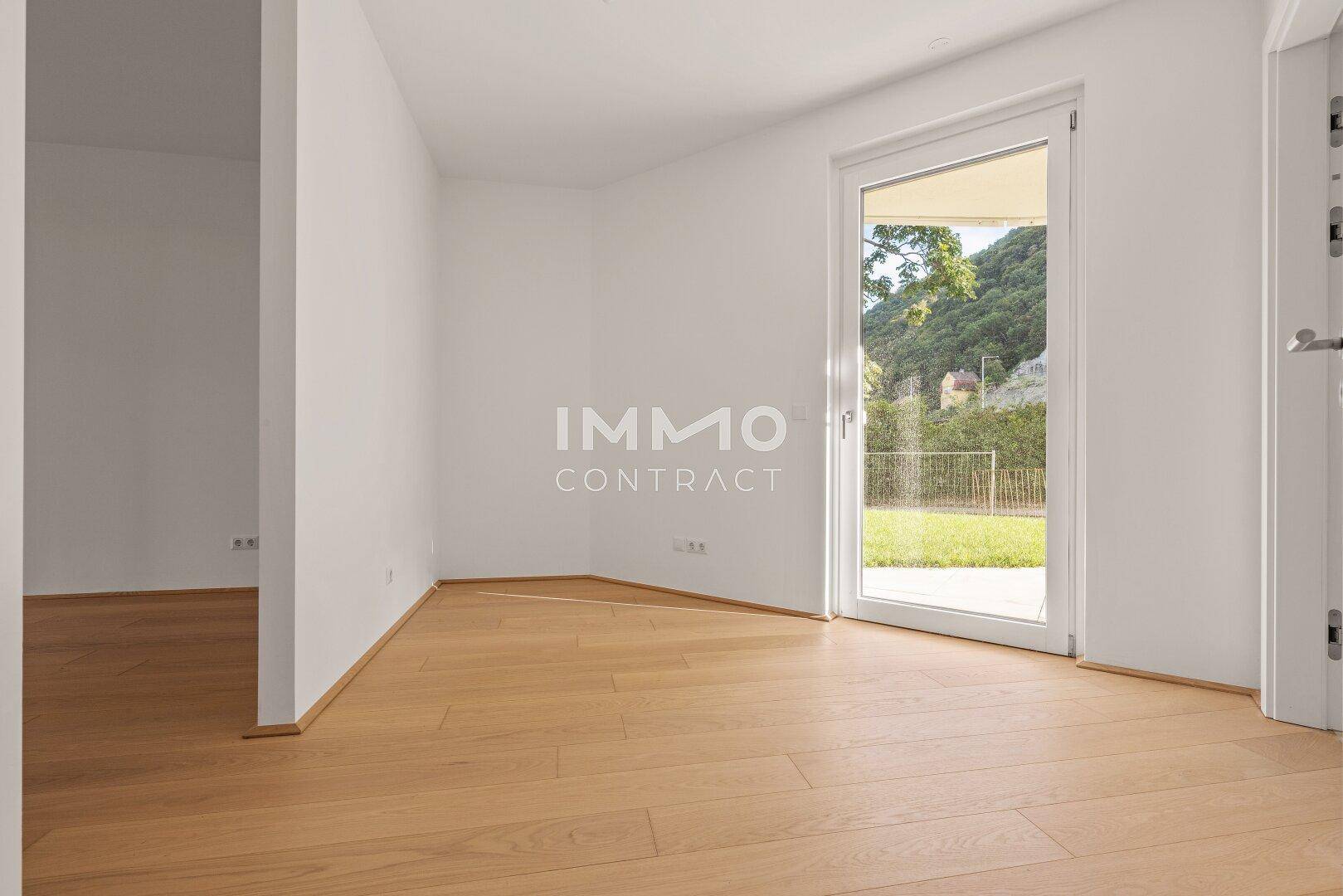 Geräumiges Schlafzimmer mit Holzboden und Fenster mit Blick ins Grüne.