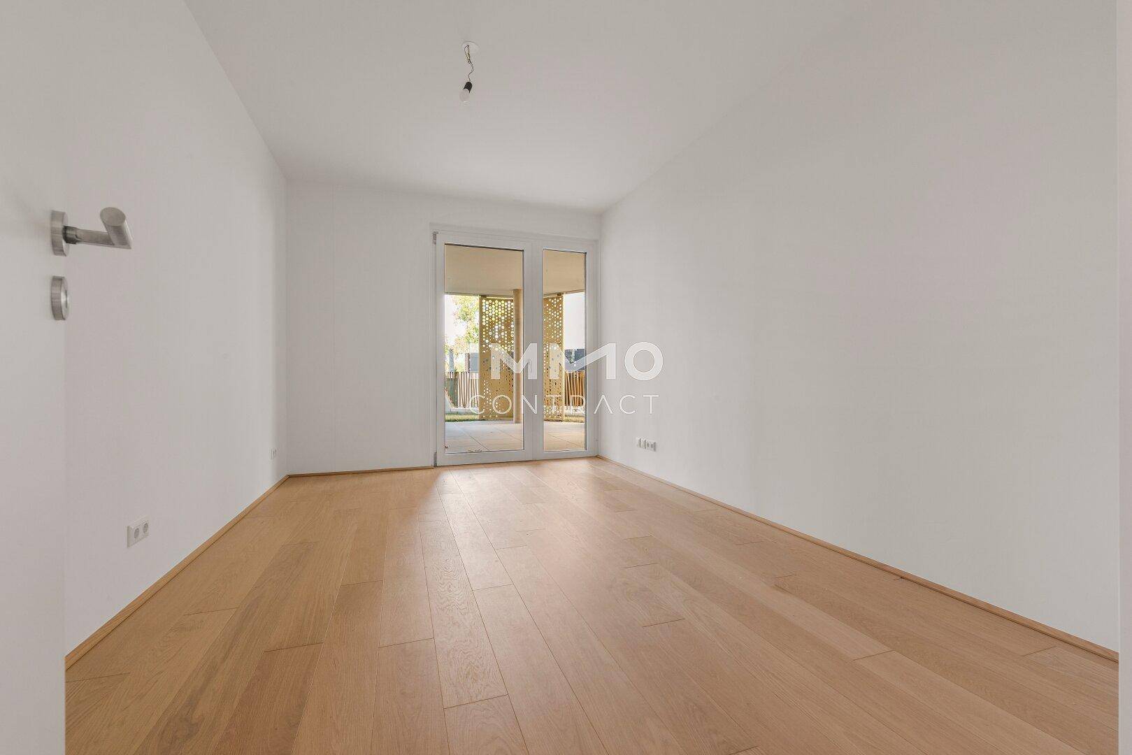 Helles Schlafzimmer mit Holzboden und direktem Zugang zu einem Balkon oder einer Terrasse.