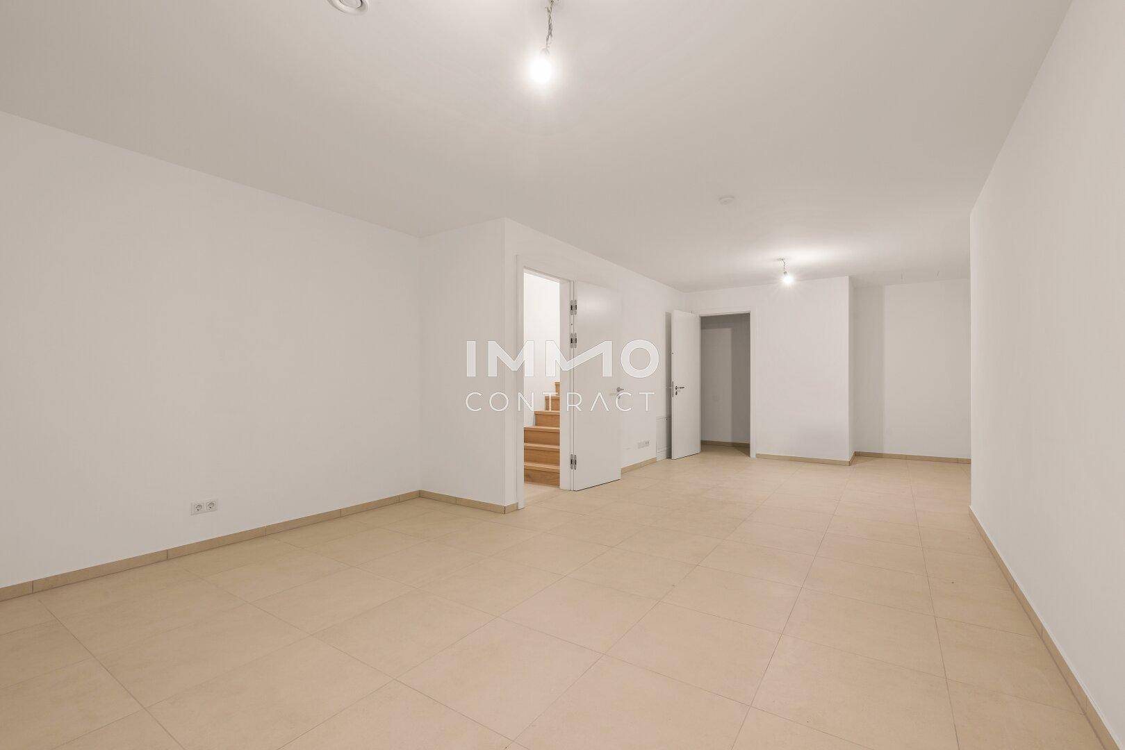 Geräumiger Raum im Untergeschoss mit Fliesenboden und Zugang zu einer Treppe.