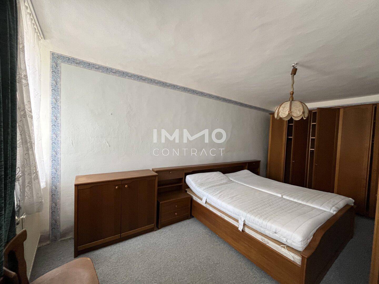 Schlafzimmer mit Doppelbett, Holzmöbeln und Teppichboden in einem traditionellen Stil.