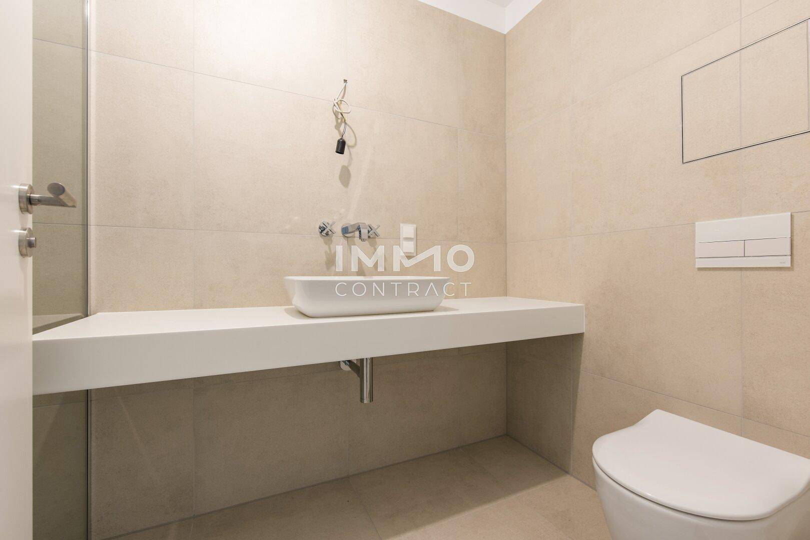Modernes Gäste-WC mit beigefarbenen Fliesen, wandhängendem WC und elegantem Aufsatzwaschbecken.