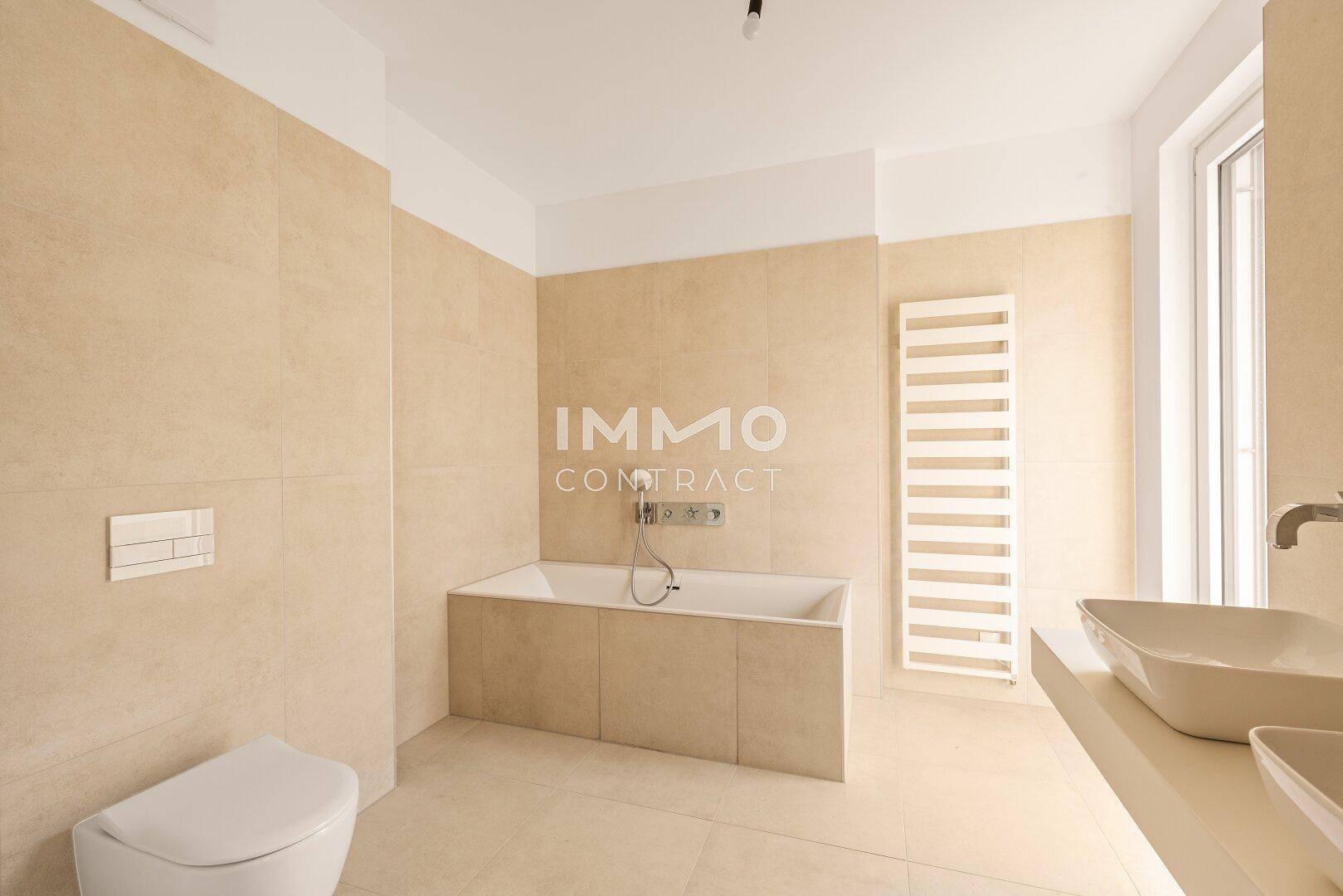 Modernes Badezimmer mit Badewanne, Doppelwaschbecken und beheiztem Handtuchhalter in neutralen Beigetönen.