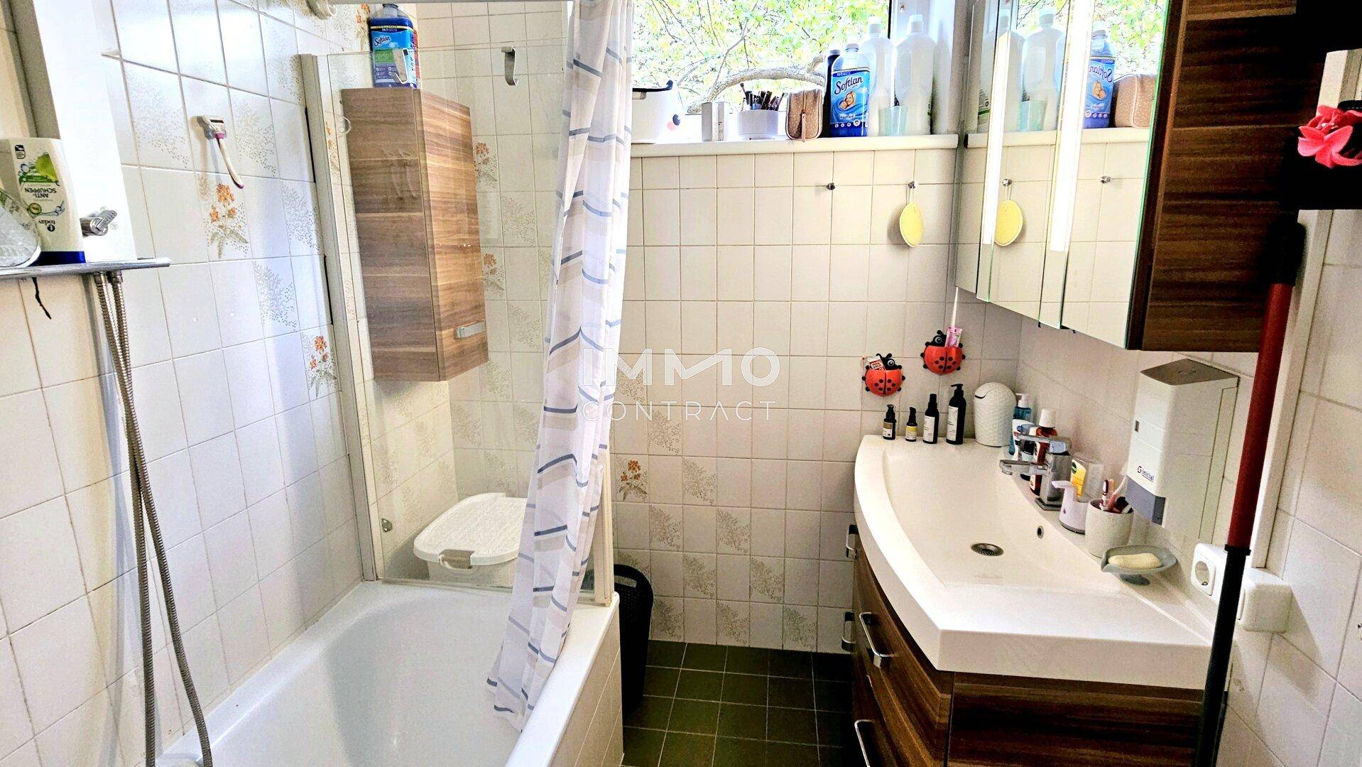 Funktionales Badezimmer mit Badewanne, Duschvorhang und Fenster für Tageslicht.
