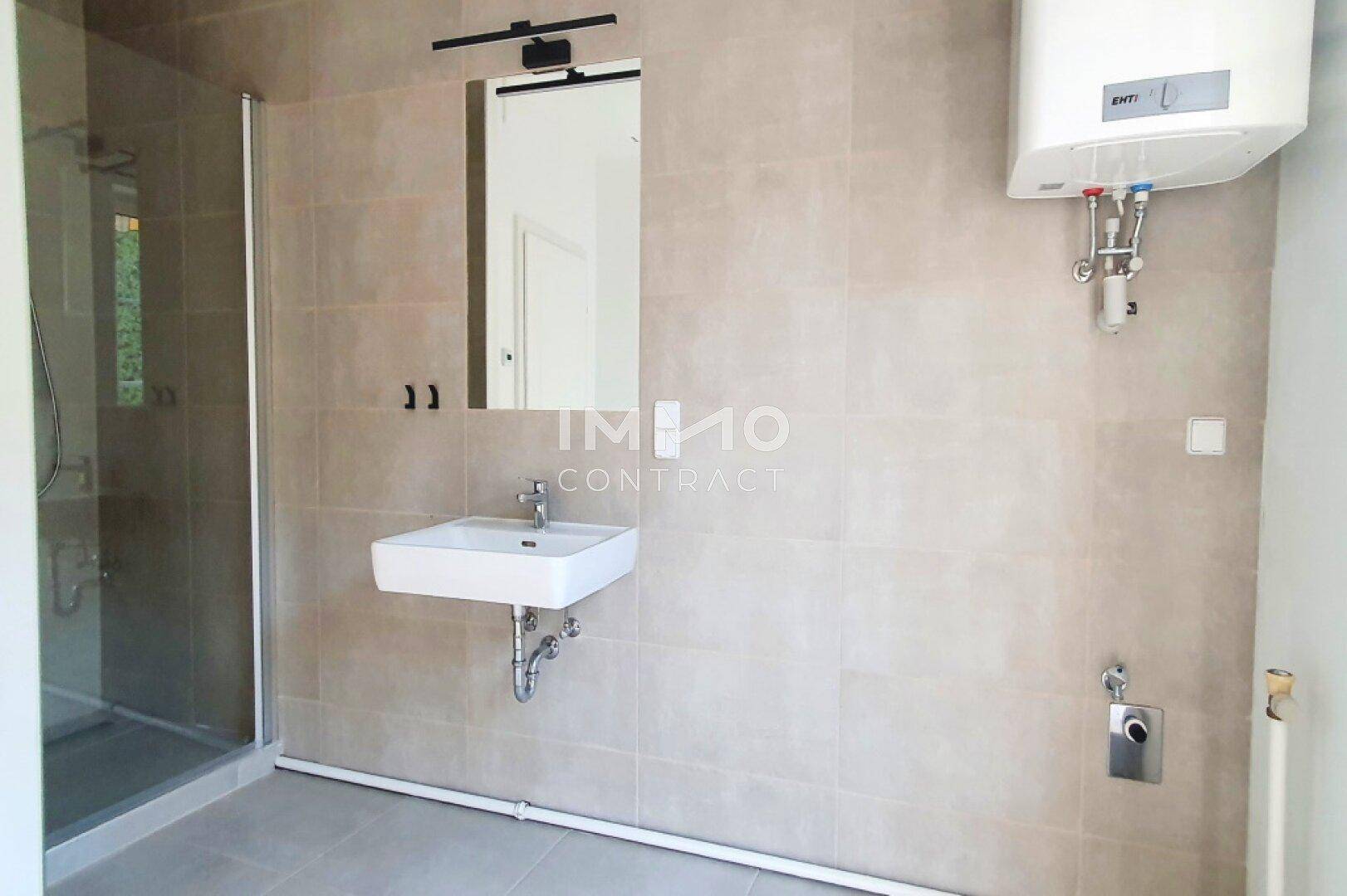 Modernes Badezimmer mit begehbarer Dusche, Wandwaschbecken und großen Fliesen.