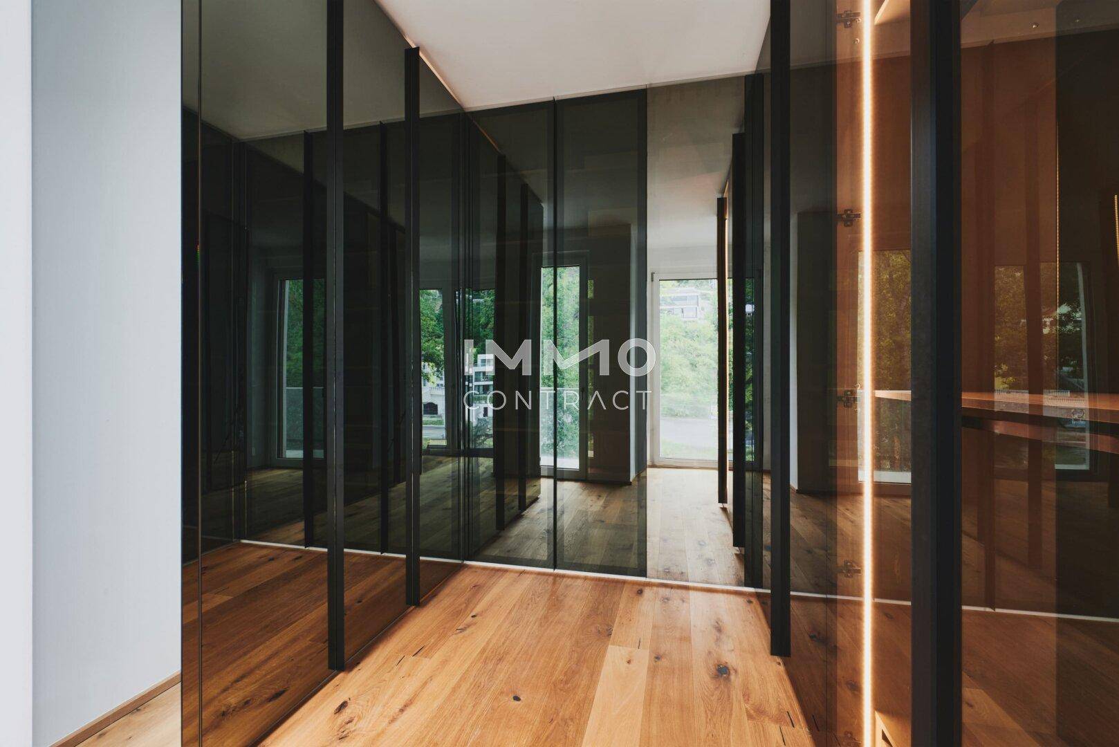 Begehbarer Kleiderschrank mit eleganten Spiegeltüren und warmem Holzboden.