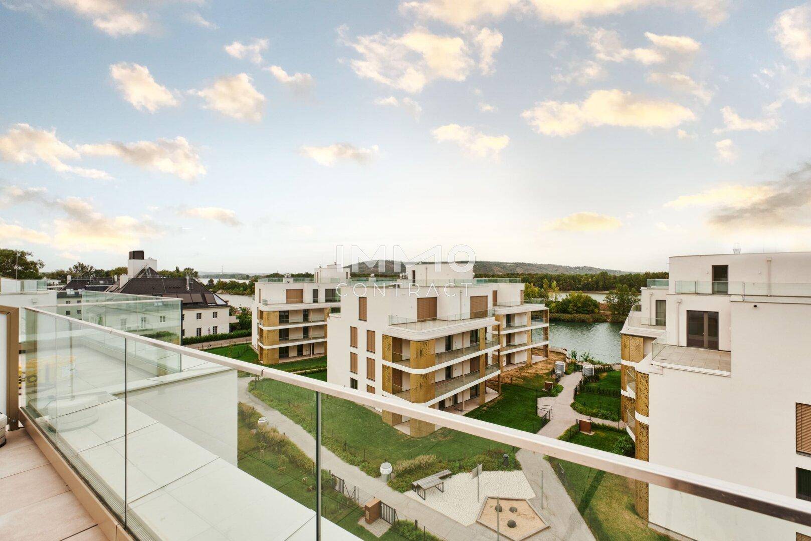 Balkon mit Glasgeländer und malerischem Blick auf den See und die moderne Architektur.