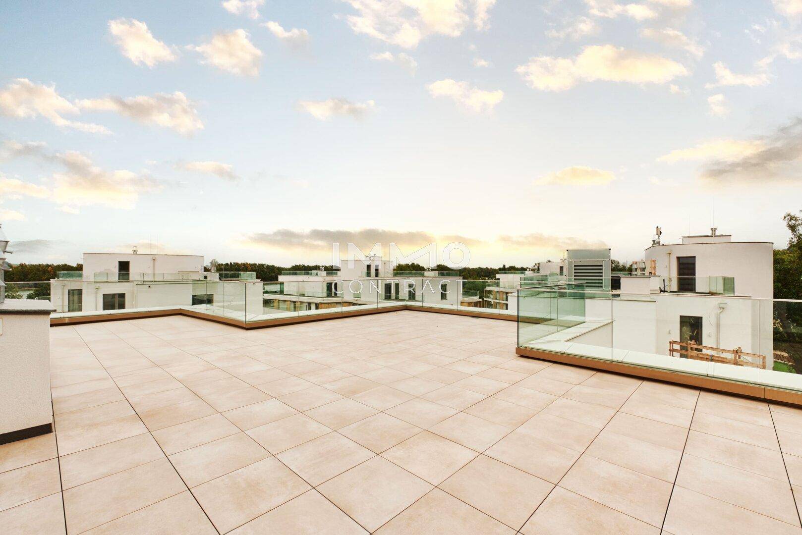 Sonnige Dachterrasse mit weitem Panoramablick über die Dächer der modernen Wohnanlage.