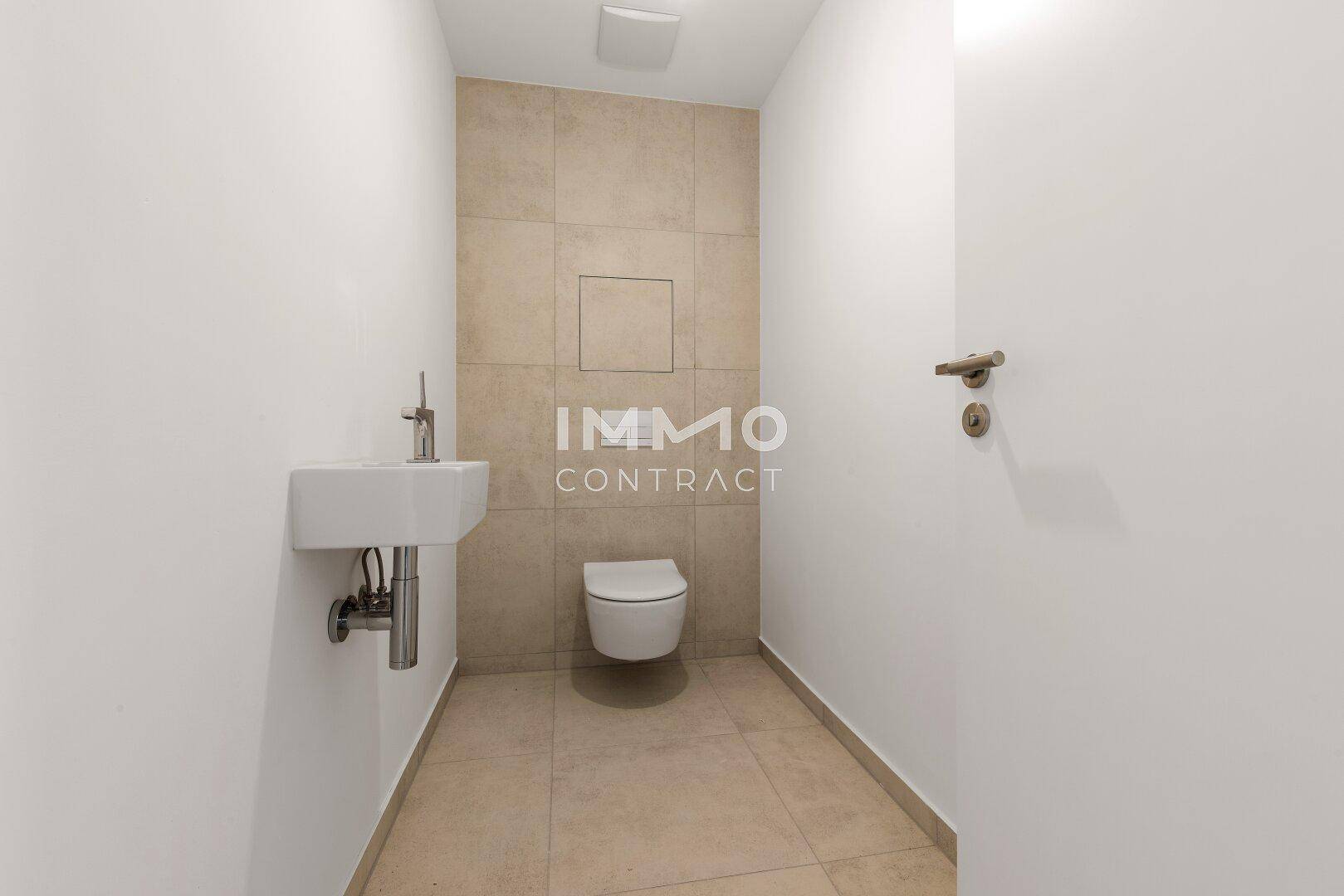 Modernes Gäste-WC mit Wand-WC, kleinem Waschbecken und beigefarbenen Fliesen.