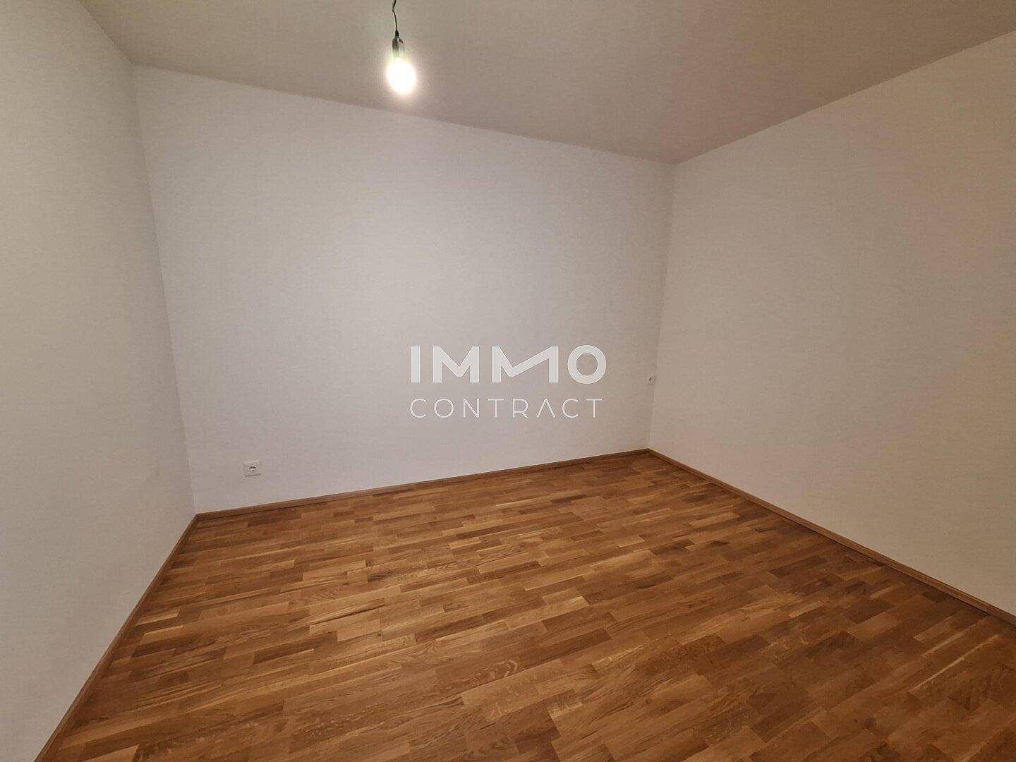 Geräumiges, leeres Zimmer mit neuem Parkettboden und weißen Wänden, bereit zur Einrichtung.