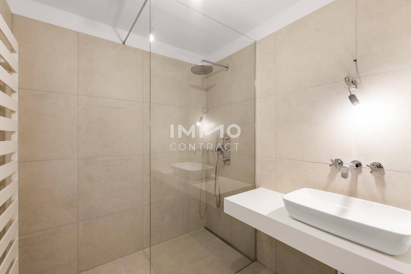 Modernes Badezimmer mit beigefarbenen Fliesen, einer begehbaren Dusche und einem eleganten Waschbecken.