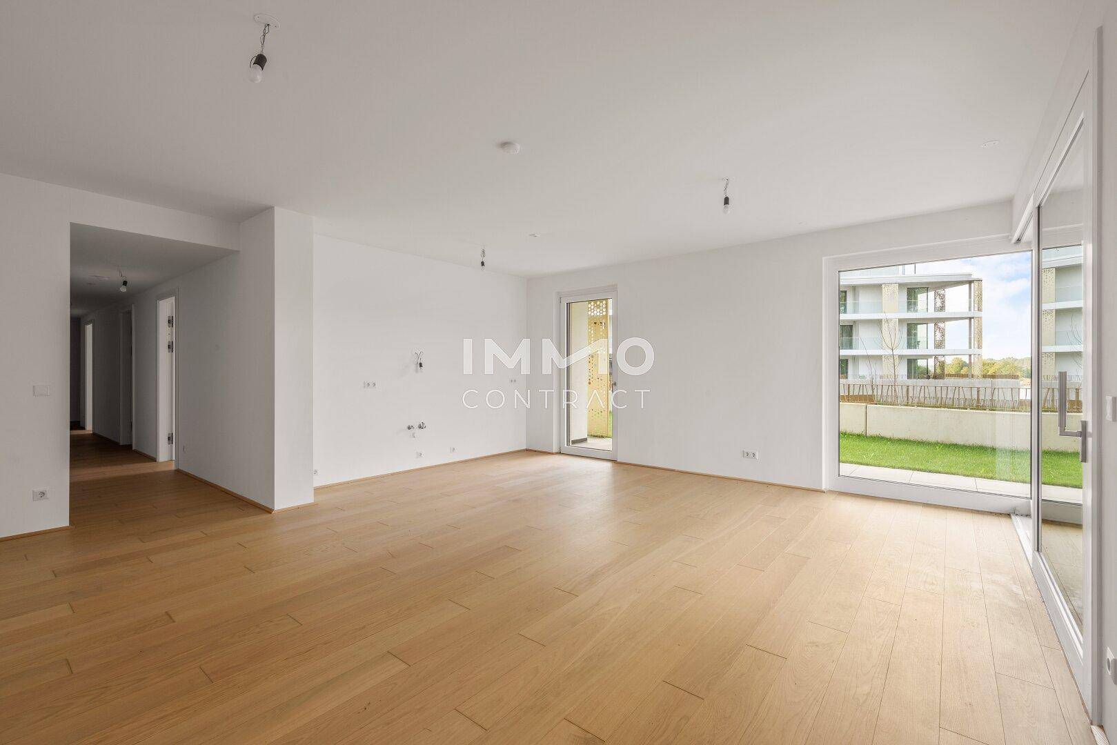 Geräumiger, lichtdurchfluteter Wohnbereich mit hellem Parkettboden und großen Fensterfronten.