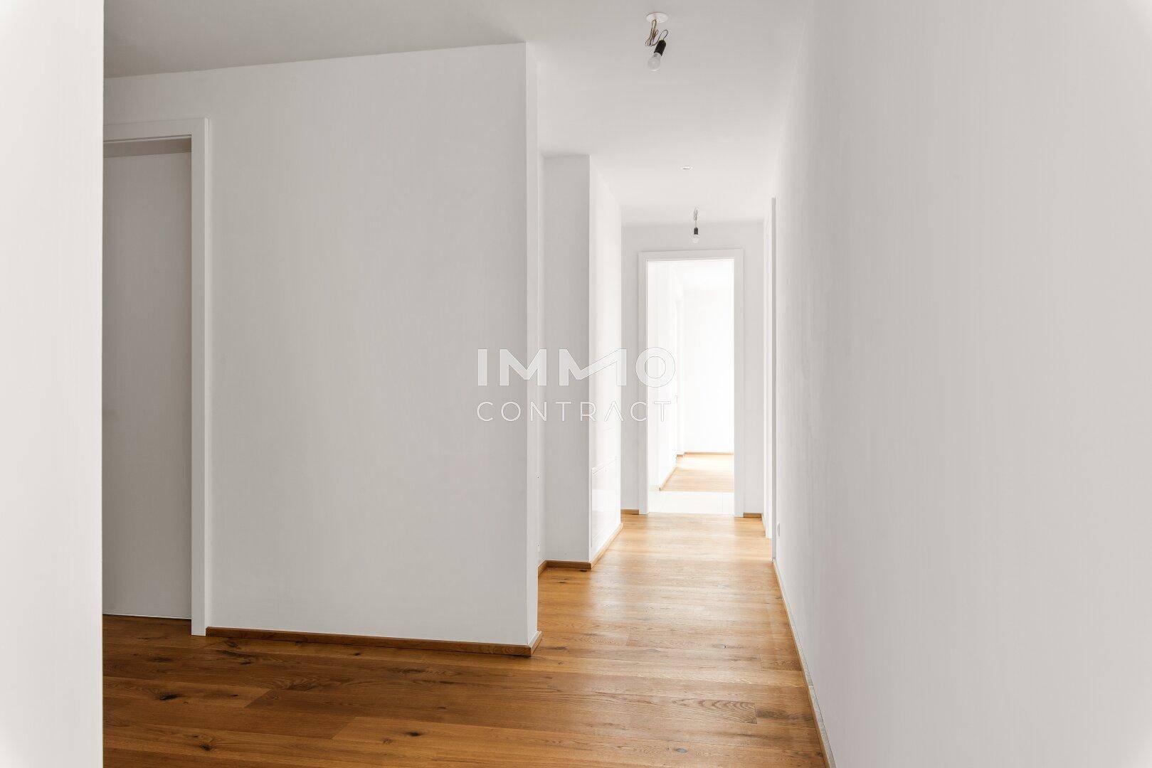 Langer, heller Flur mit Holzboden, der zu weiteren Räumen führt.