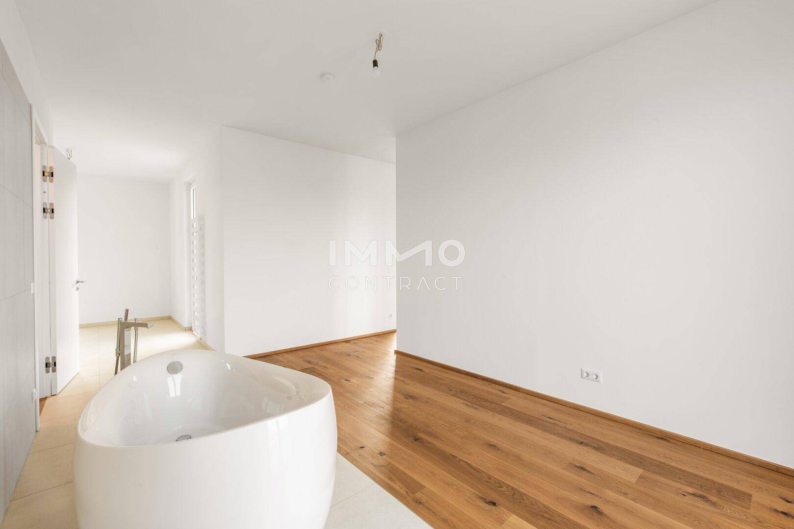 Heller Raum mit Holzboden und einer modernen freistehenden Badewanne.