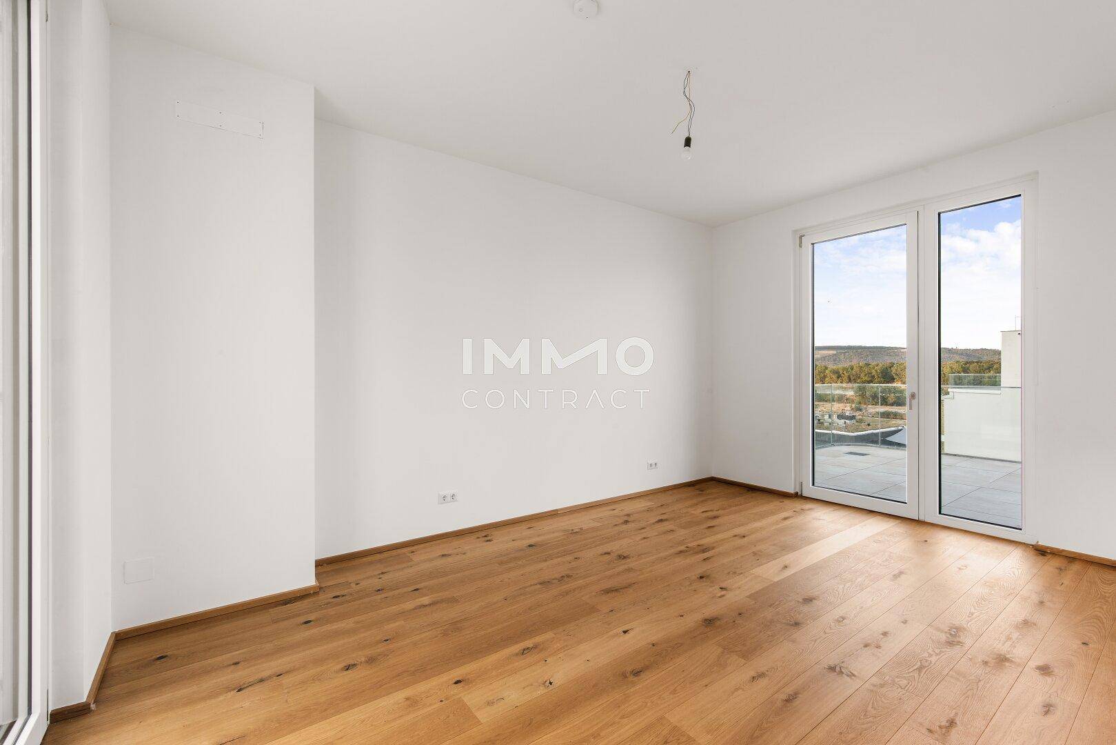 Helles Schlafzimmer mit Holzboden und Zugang zu einer Außenterrasse.