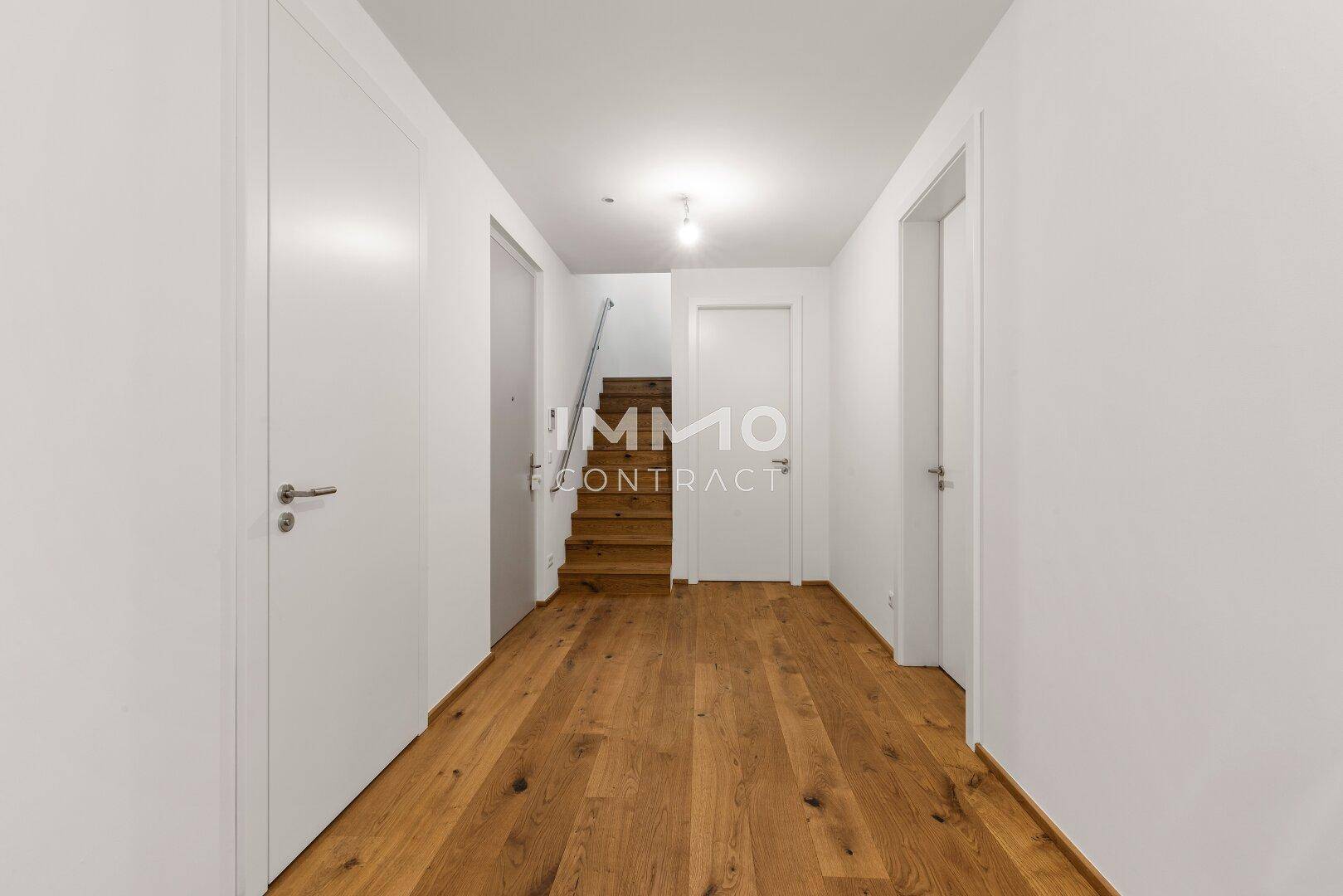 Heller Flur mit Holzboden und Treppe, die in eine andere Etage führt.