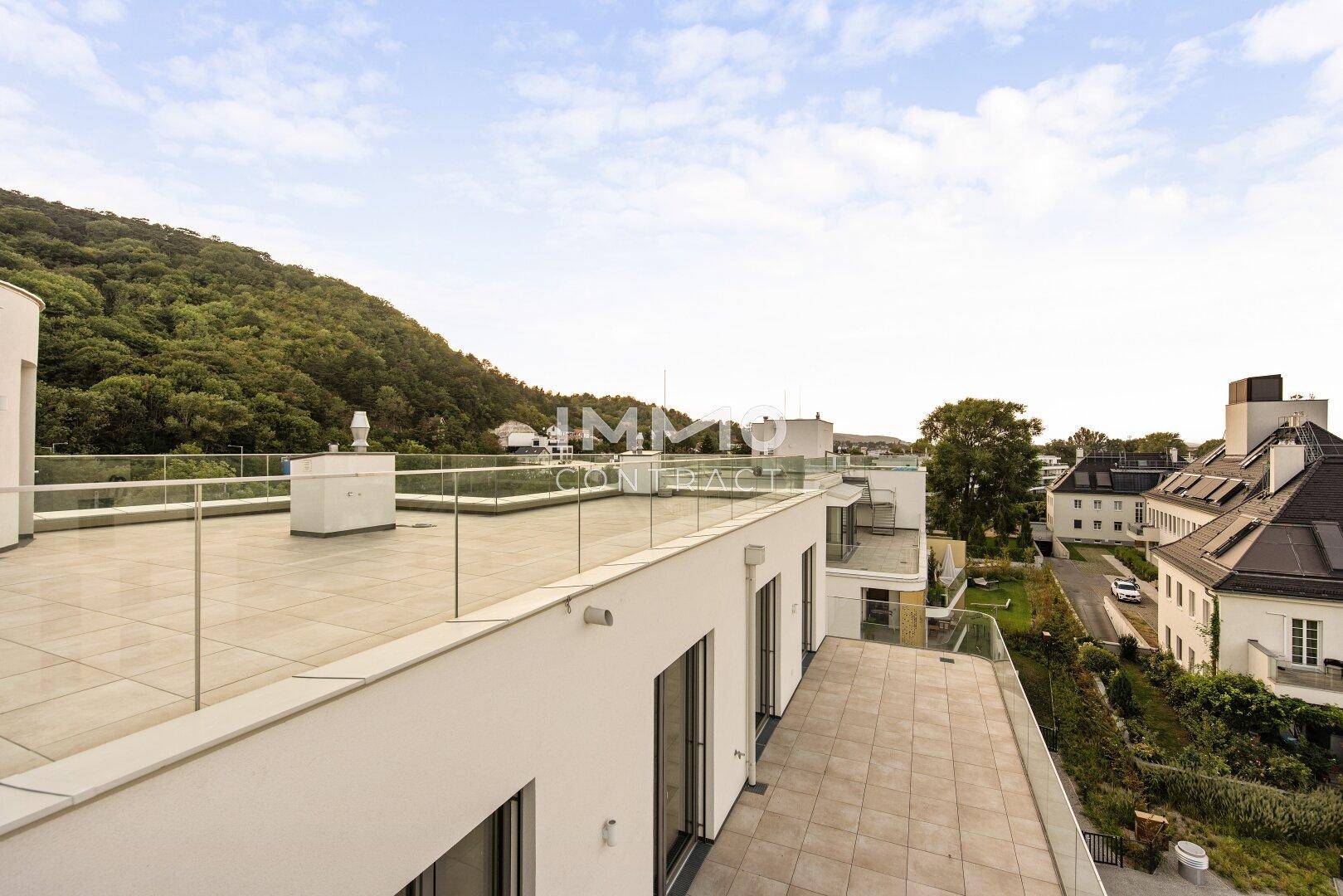 Weitläufige Dachterrasse mit Blick auf die umliegenden Gebäude und die grüne Landschaft.