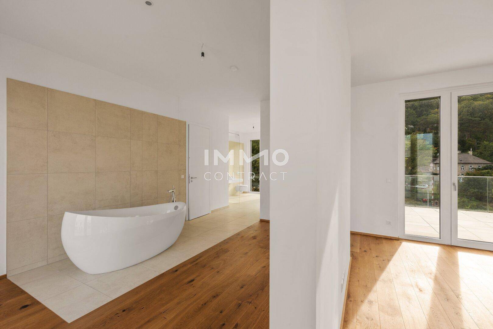 Helles Schlafzimmer mit Holzboden und freistehender Badewanne, die einen luxuriösen Akzent setzt.
