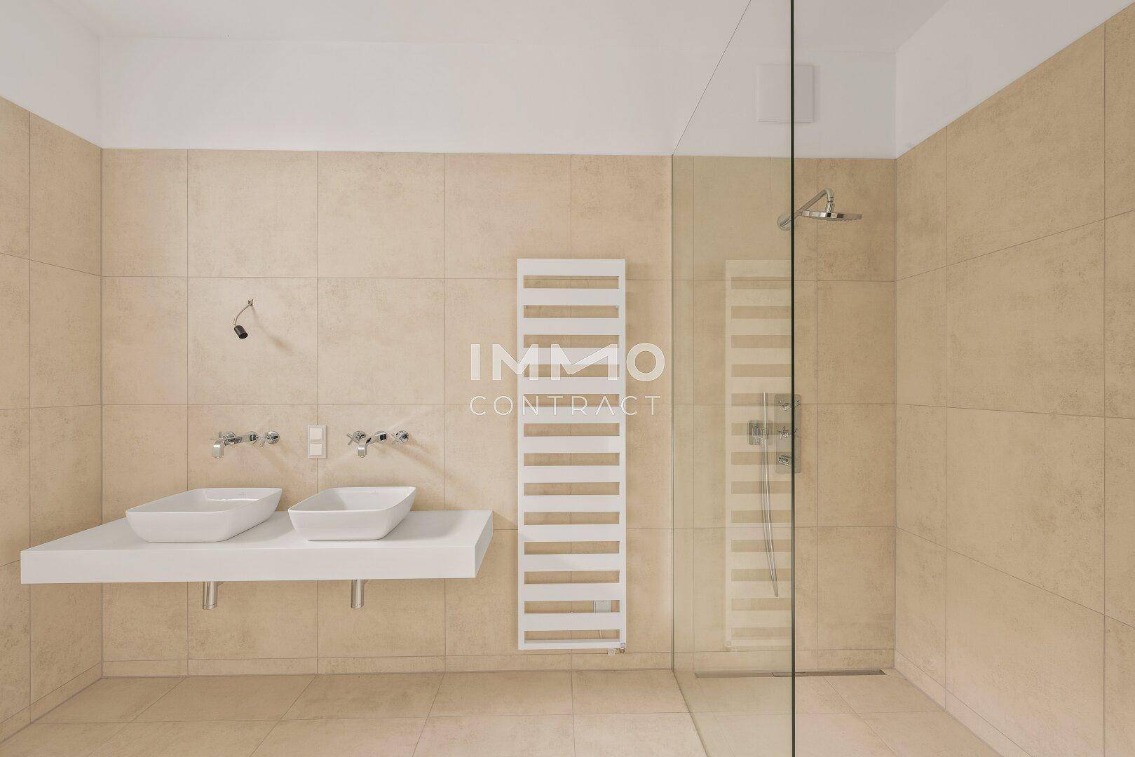 Modernes Badezimmer mit beigefarbenen Fliesen, Doppelwaschbecken und großer begehbarer Dusche.